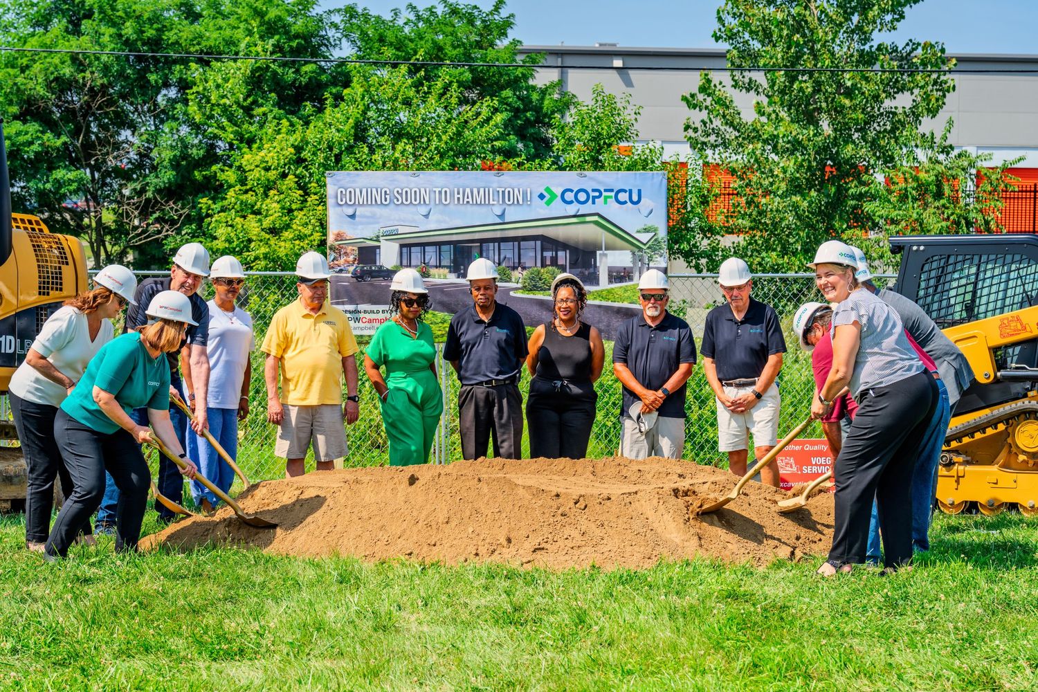 Group actively shoveling dirt together at COPFCU new location groundbreaking ceremony.
