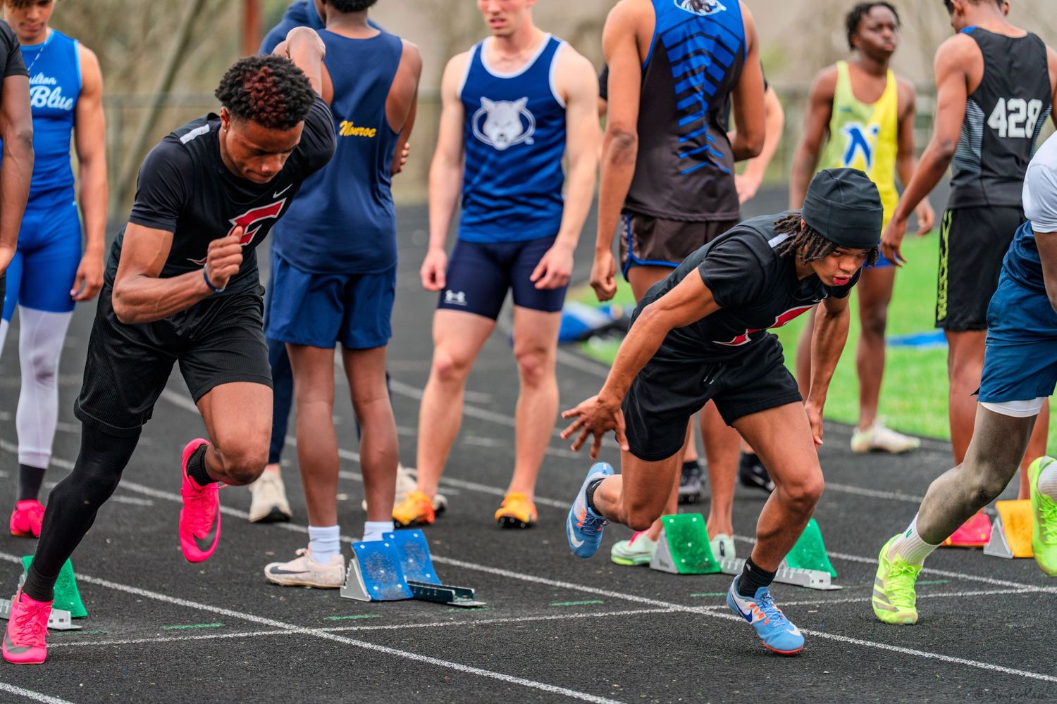 Athletes sprint from starting blocks during an outdoor track and field competition.