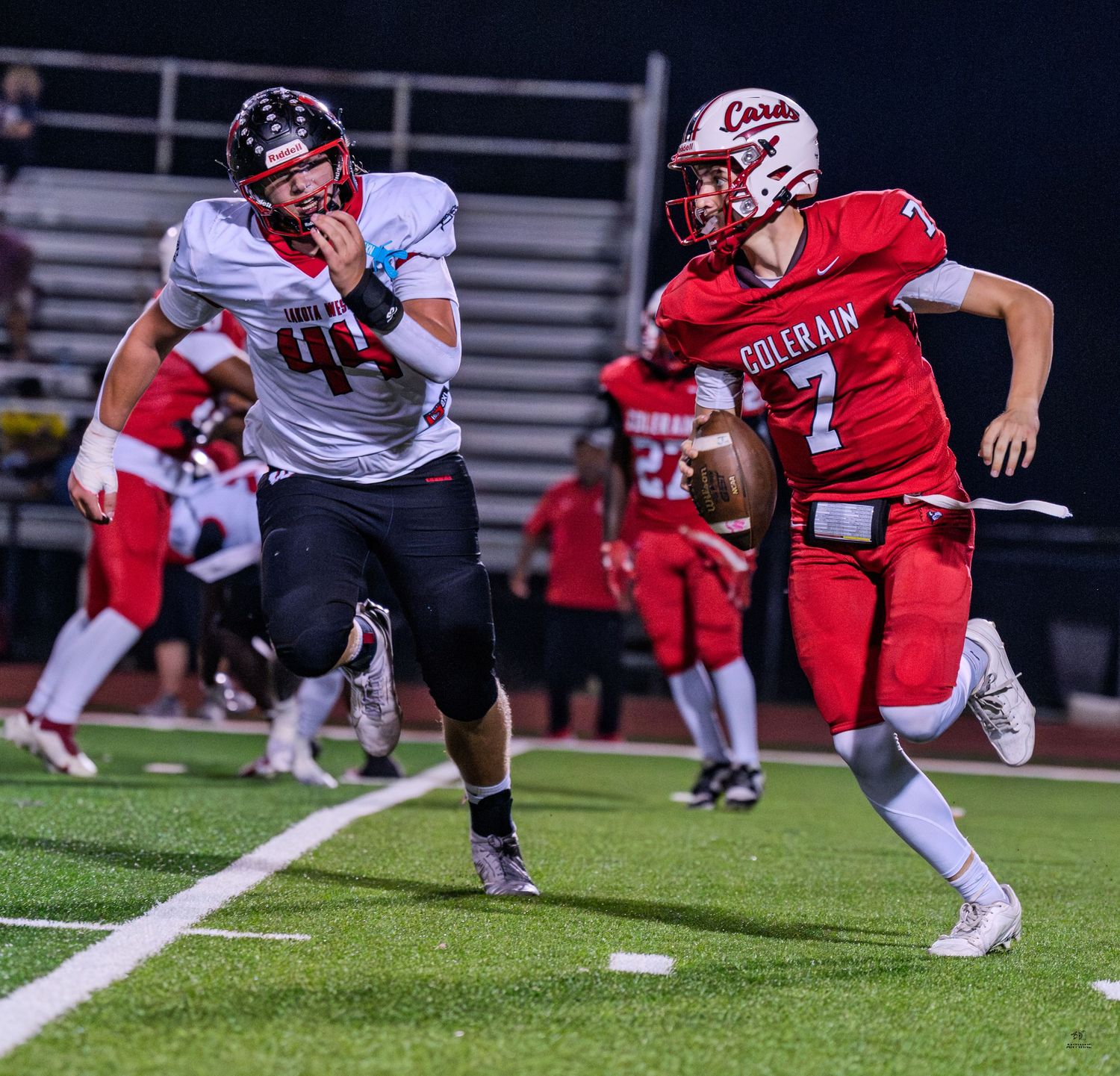 Colerain Cardinals quarterback #7 scrambles away from a defender during a night game.
