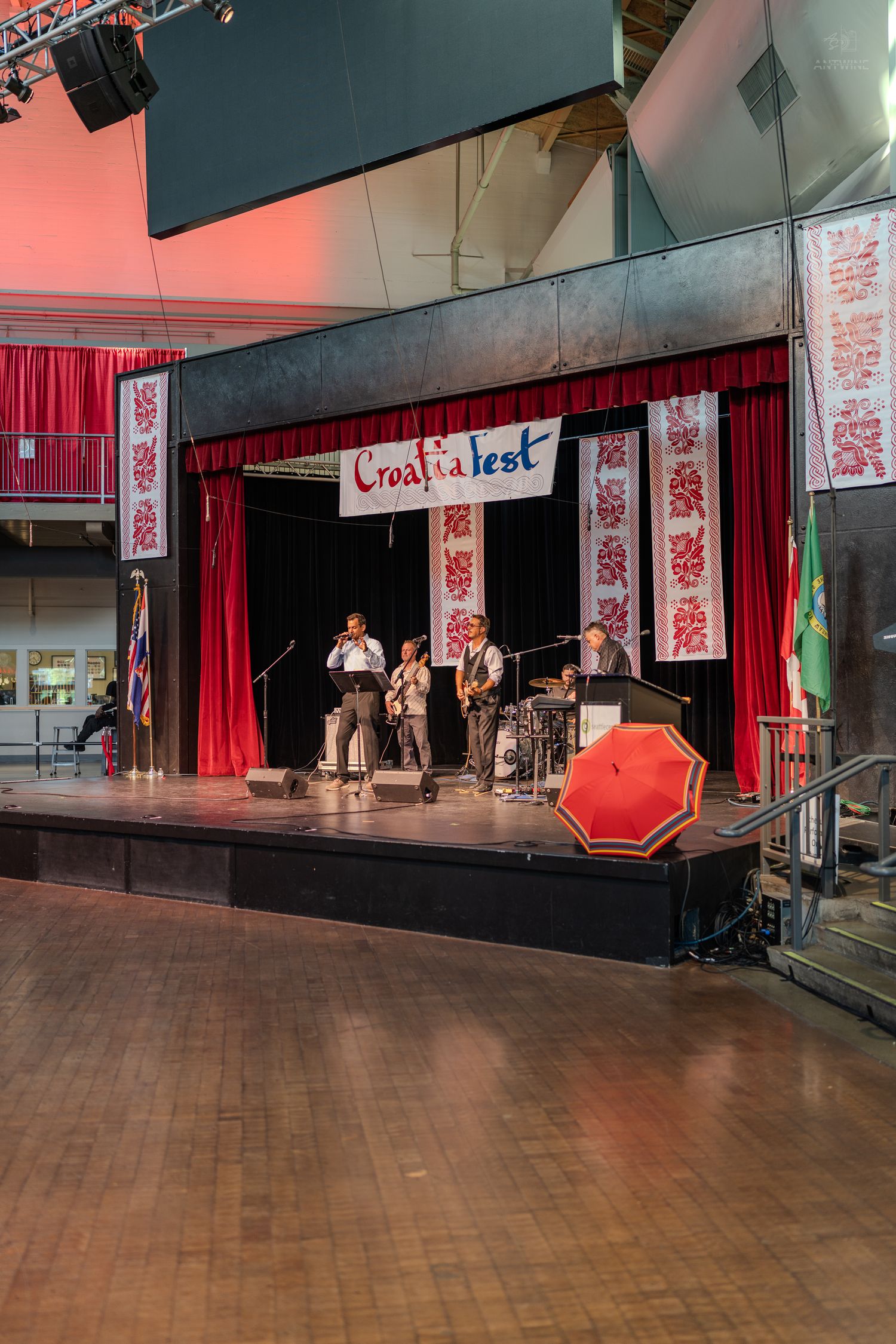 Band performing on stage at CroatiaFest with red curtains and decorative banners.