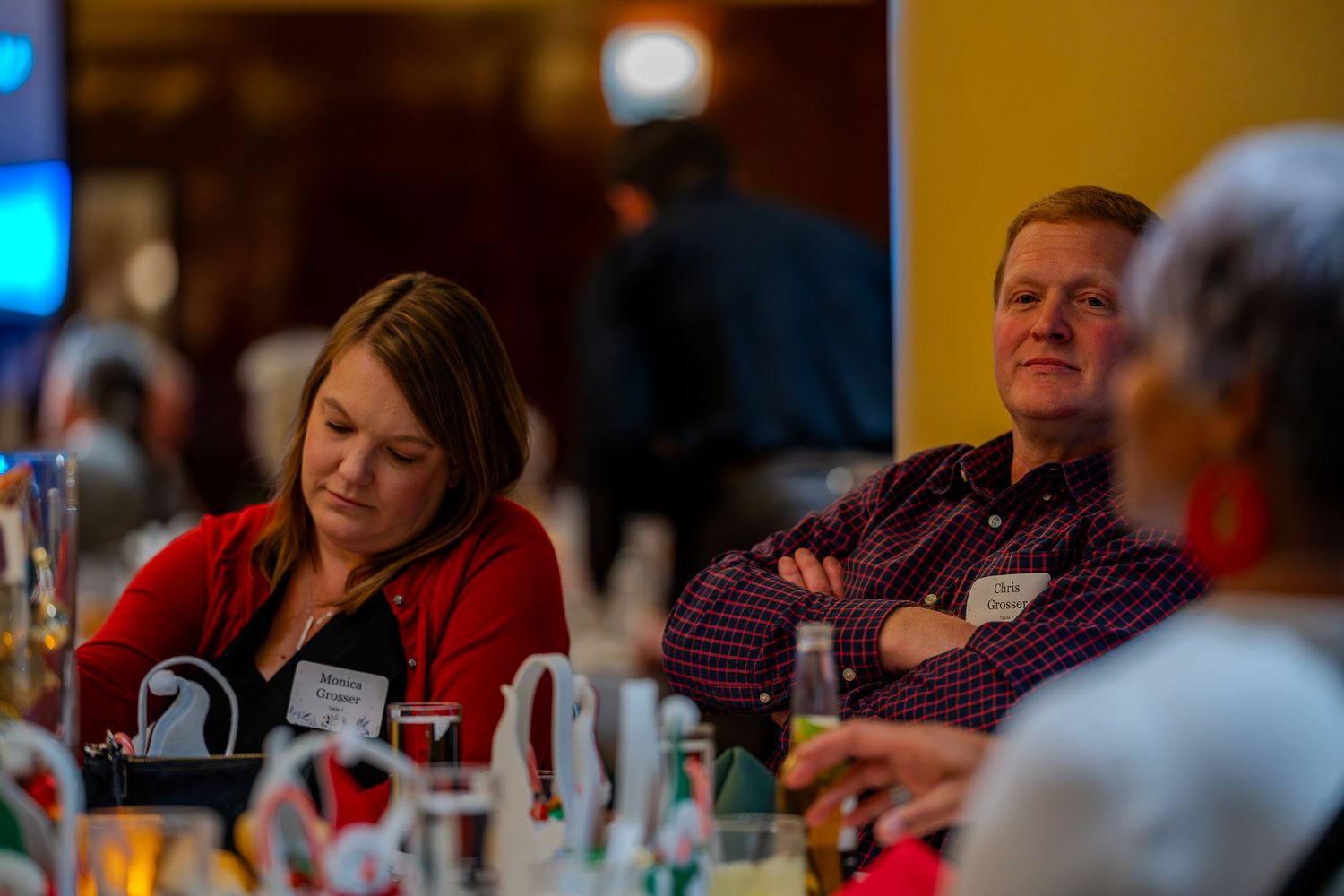 Two professionals sit at a conference table, listening attentively during a business event or seminar.