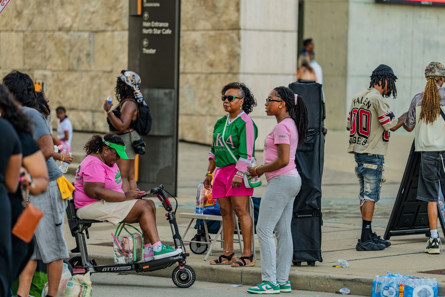 Group of people standing outside a building on a city sidewalk during a daytime event.