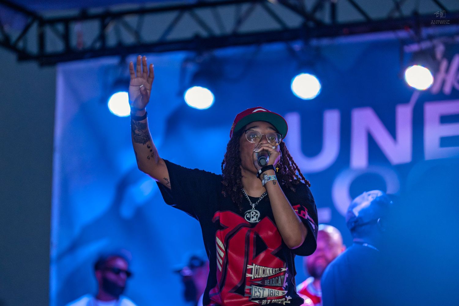 Performer raising hand while singing into microphone on stage at Juneteenth Block Party event.