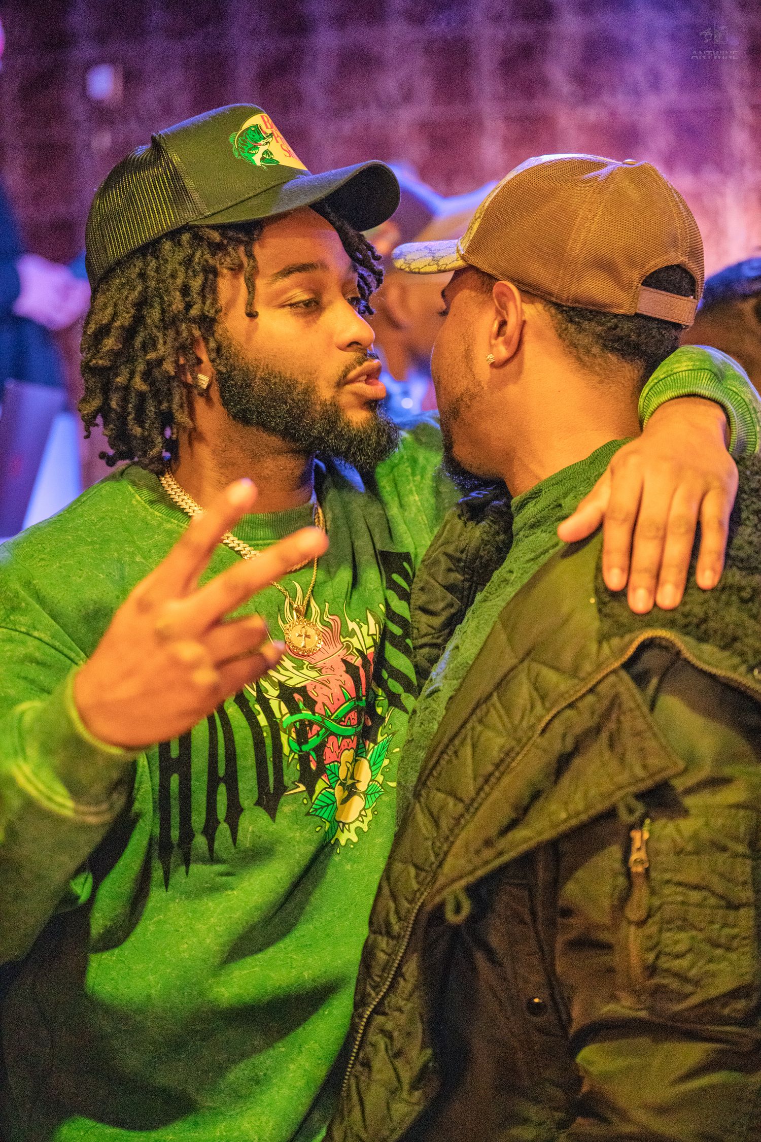 Two men in green outfits sharing a moment at a vibrant nightclub event.