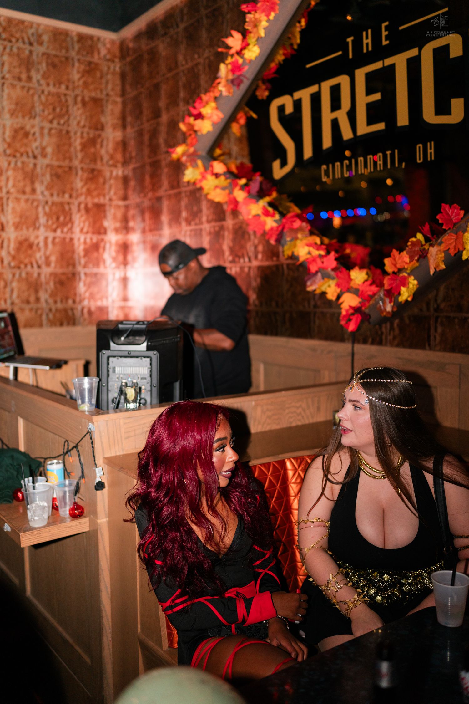 Two women in Halloween costumes chatting in a booth at The Stretch bar in Cincinnati OH.