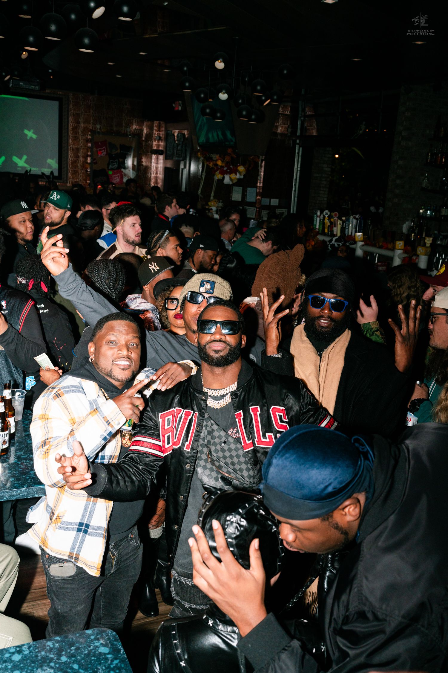 Group of friends celebrating at a crowded bar wearing Bulls and streetwear.