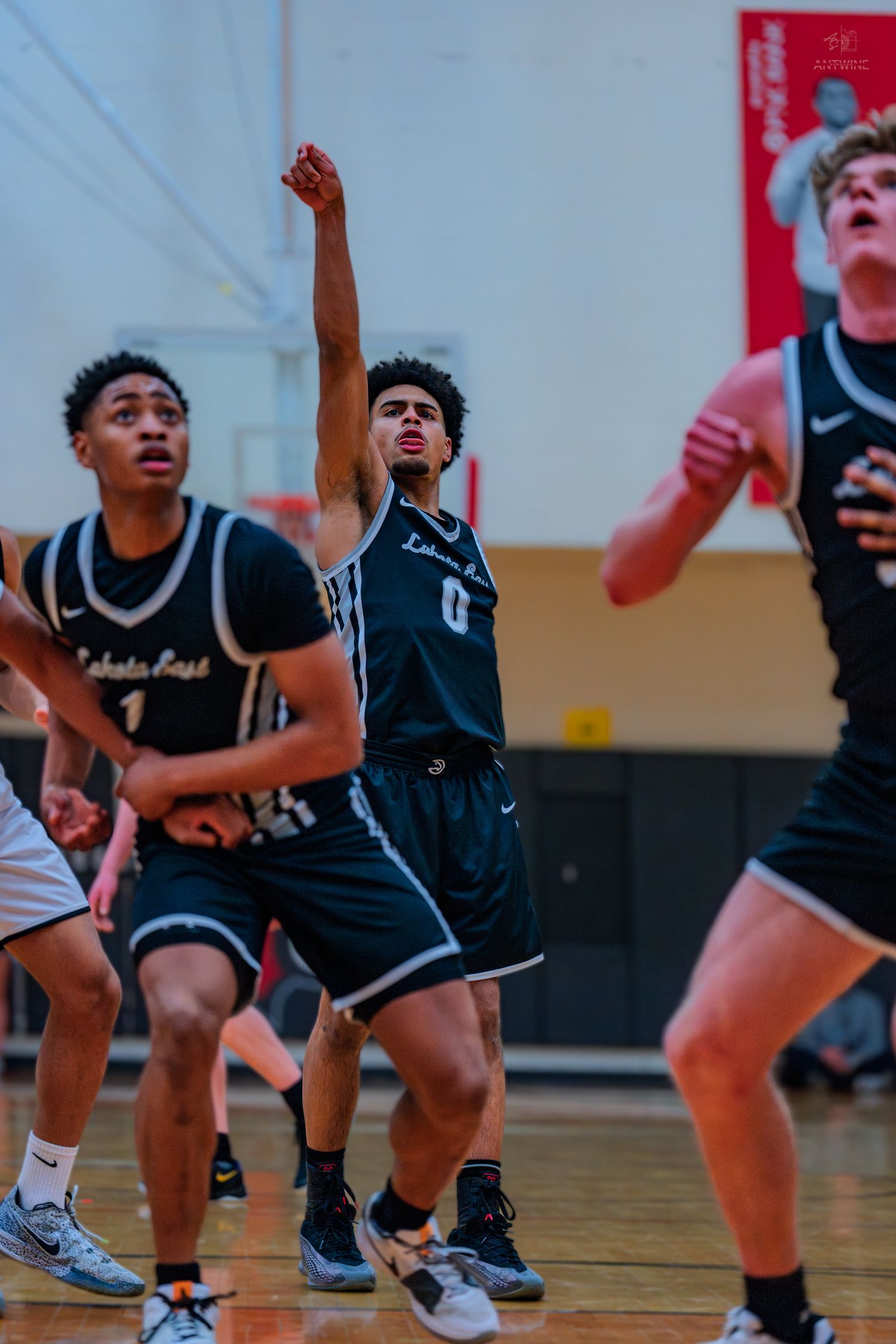 Lakota East player #0 raises fist after shooting during competitive high school basketball game.
