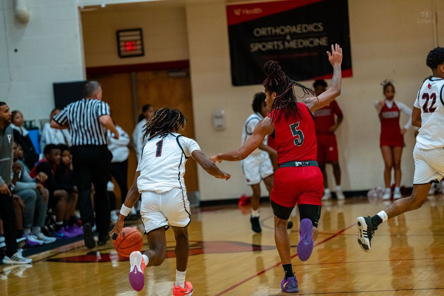 A girls basketball player in white dribbles past a defender in red during a high school basketball game.
