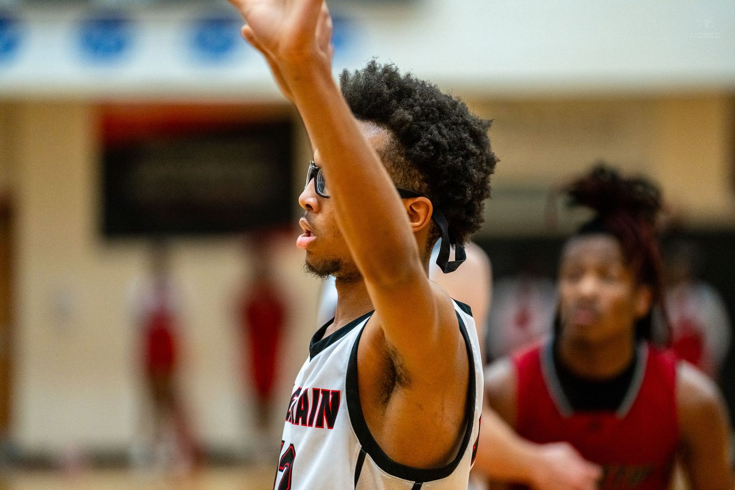 High school basketball player shoots the ball during a competitive game in a packed gymnasium.