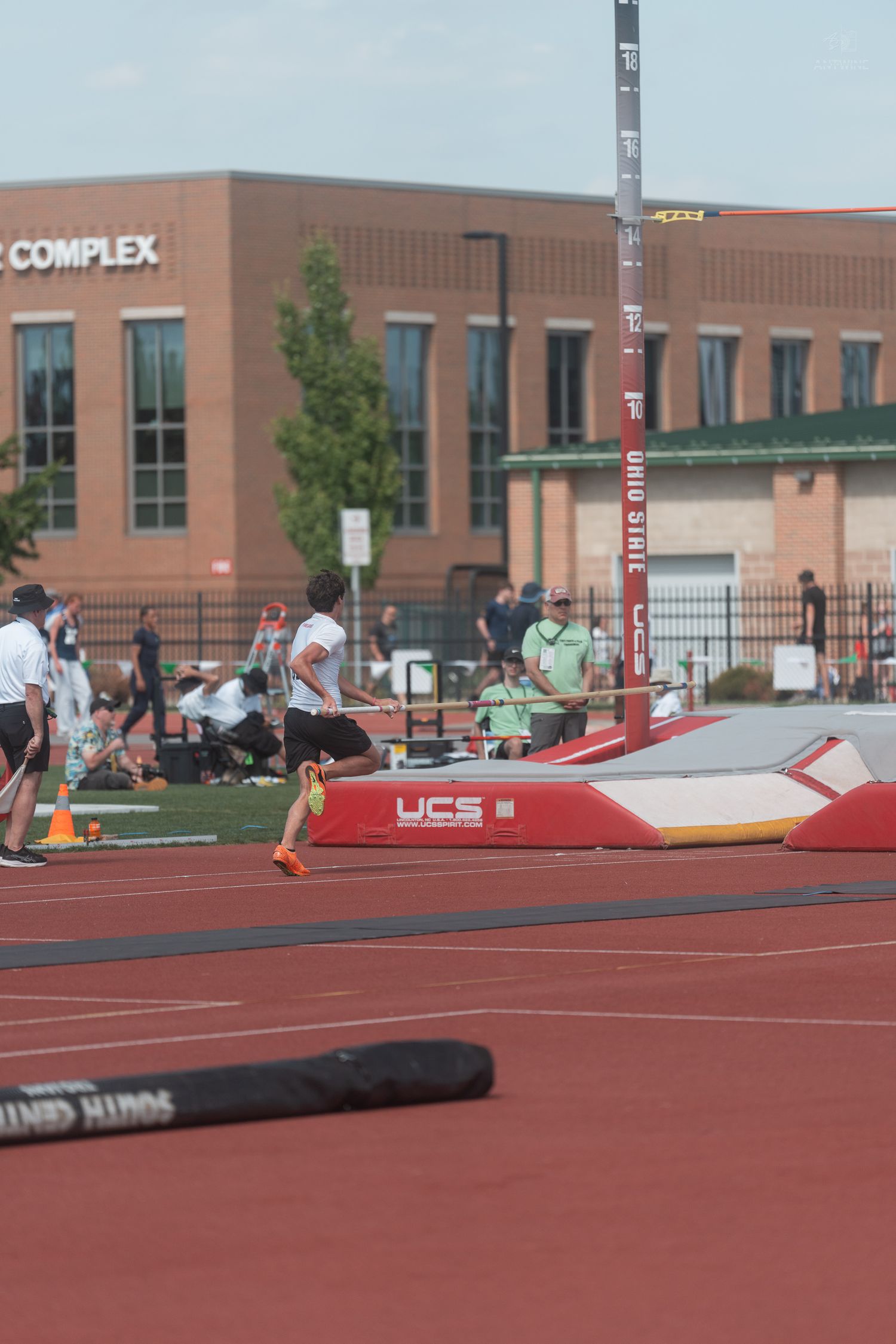 Athlete prepares for pole vault at Ohio State track complex during a competitive meet.