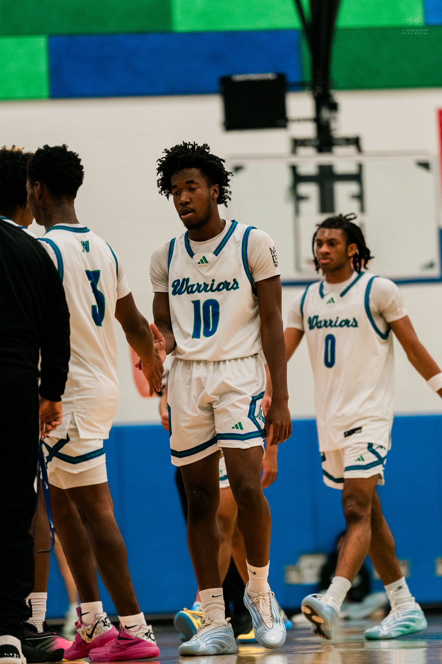 Xavier Warriors players numbers 3, 10, and 0 gather on court during a high school basketball game.