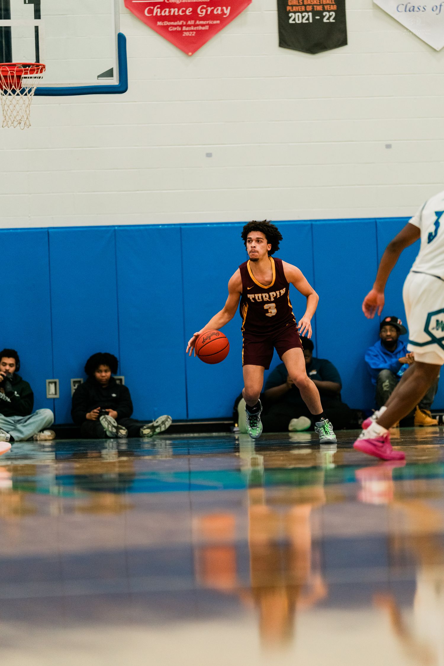 Turpin High School basketball player number 3 dribbles ball during competitive high school gym game.