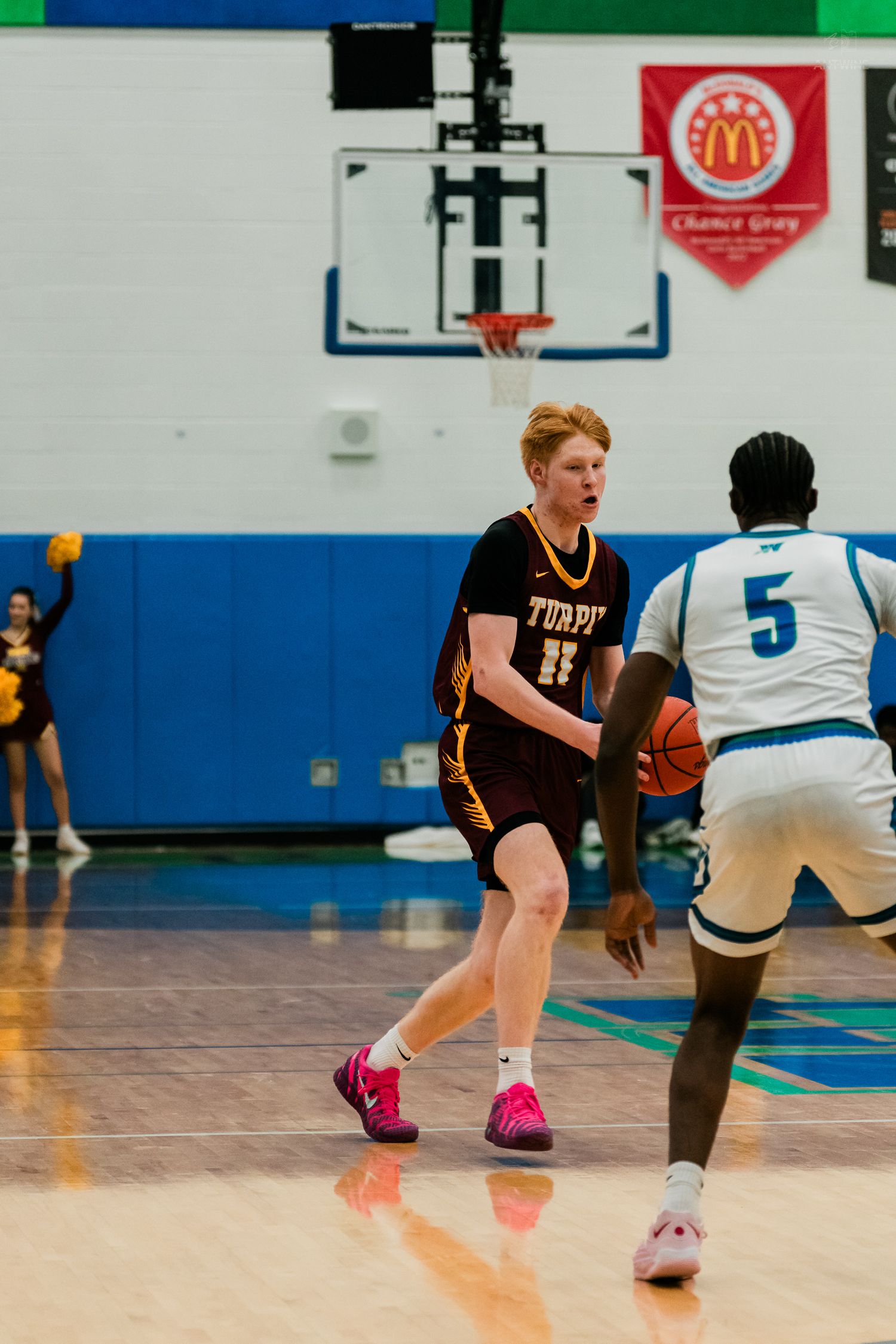 Turpin #11 red-haired guard dribbles against defender #5 in white during high school basketball.