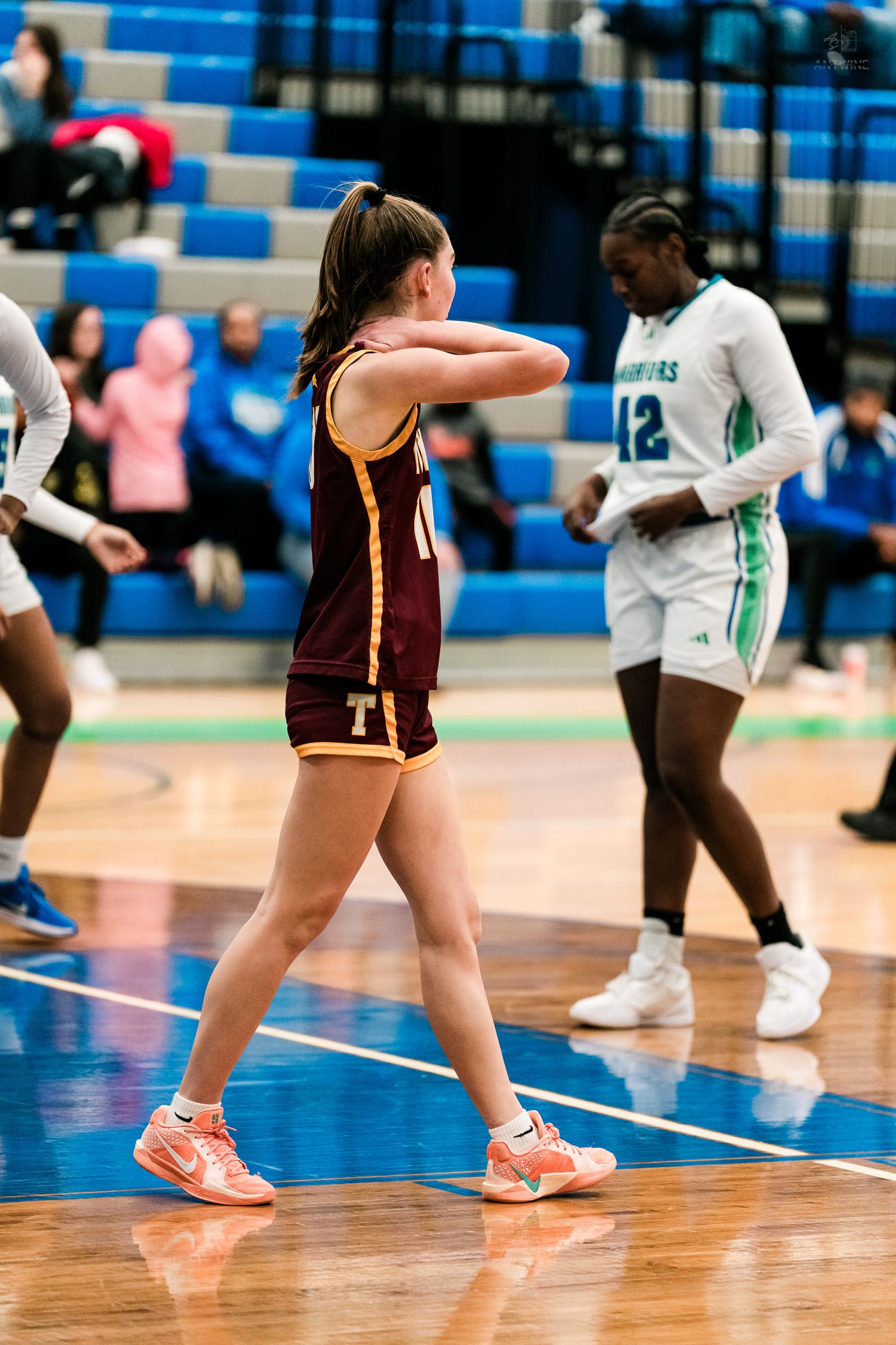 A Turpin High School girls basketball player stretches her arm during a game in a blue gymnasium.