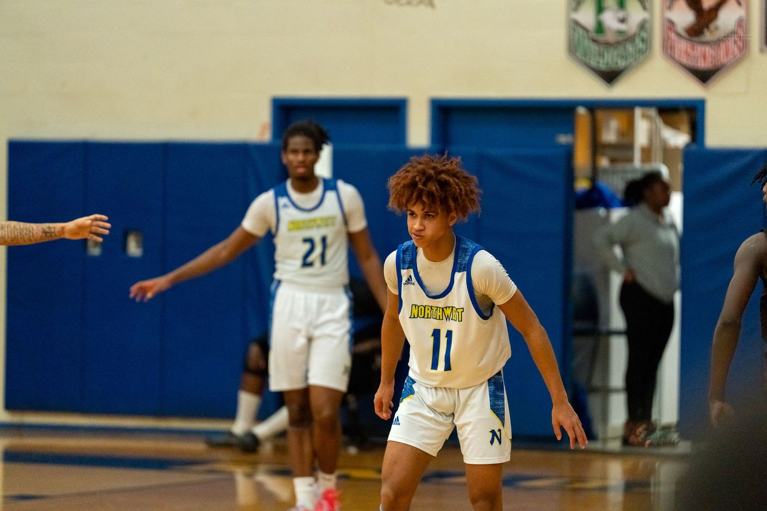 Player #11 dribbles during a high school basketball game while teammate #21 stands ready in the background.