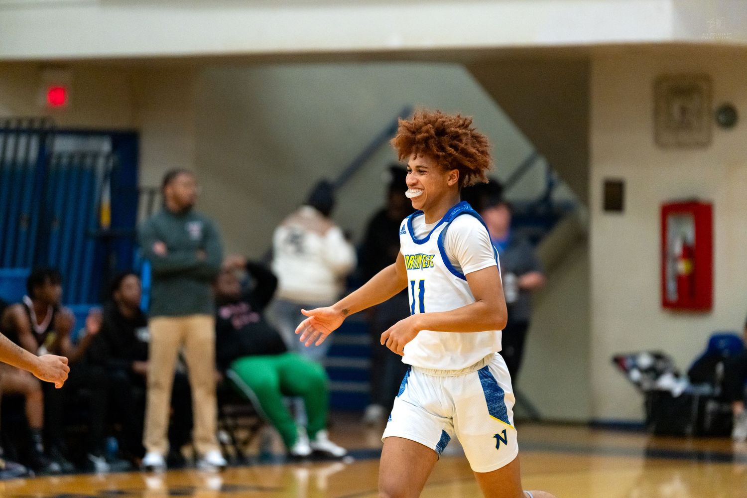 Young basketball player in blue number 11 jersey celebrates during a high school basketball game.