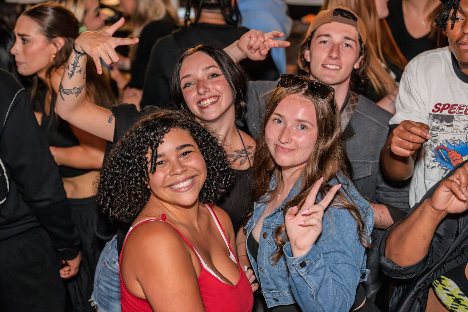 Happy group of young people smiling and making peace signs at a nighttime party.