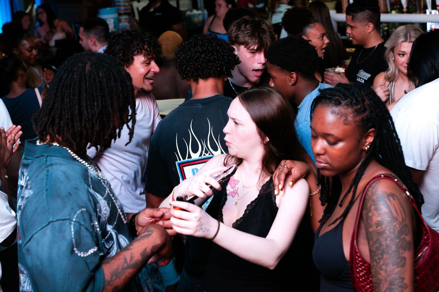 Young adults dancing and socializing at a crowded indoor nightclub party.