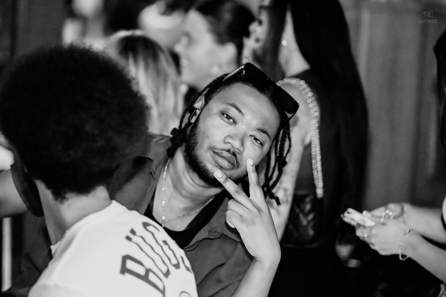 Black and white photo of man with dreadlocks gesturing at a nightclub.