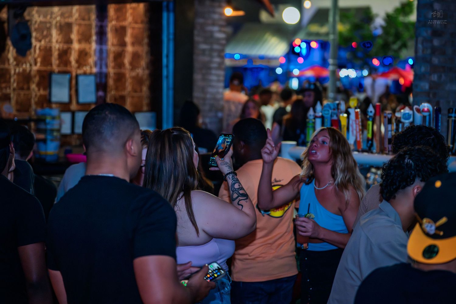 Group of people socializing and dancing at a dimly lit bar venue.
