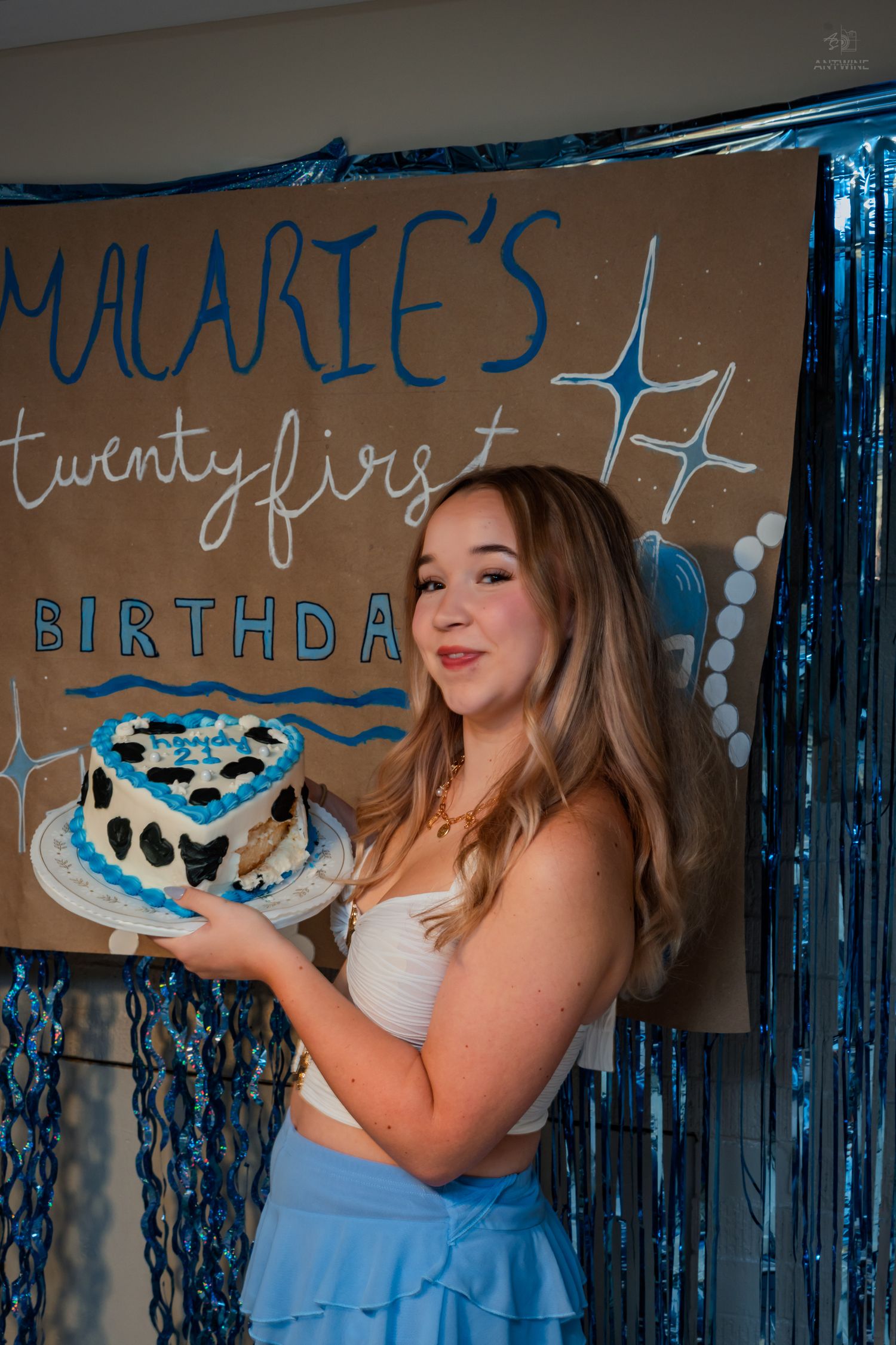 Smiling young woman proudly displays heart-shaped birthday cake at Malarie's 21st birthday party.
