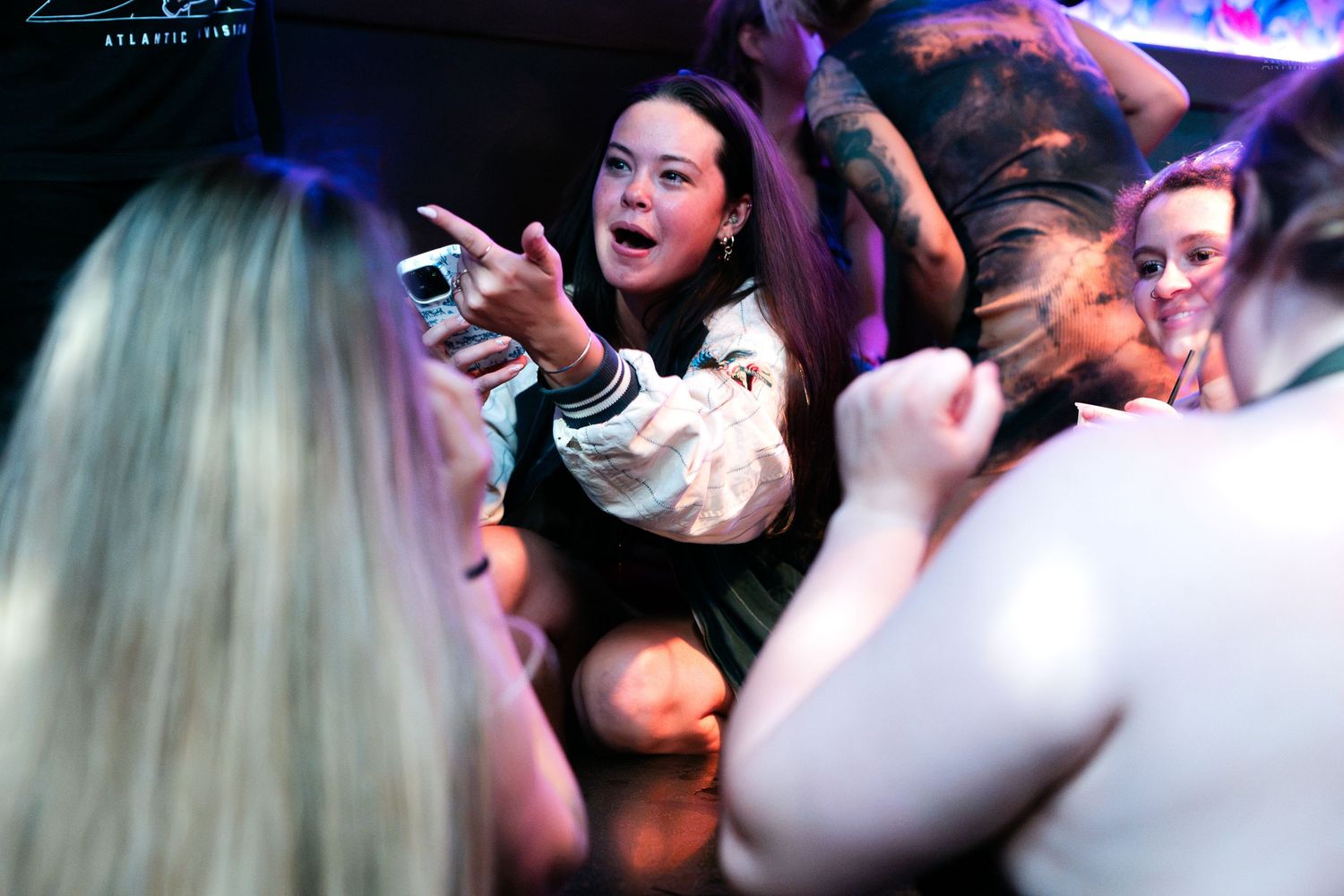 Young women dancing and taking selfies at a lively nightclub party.