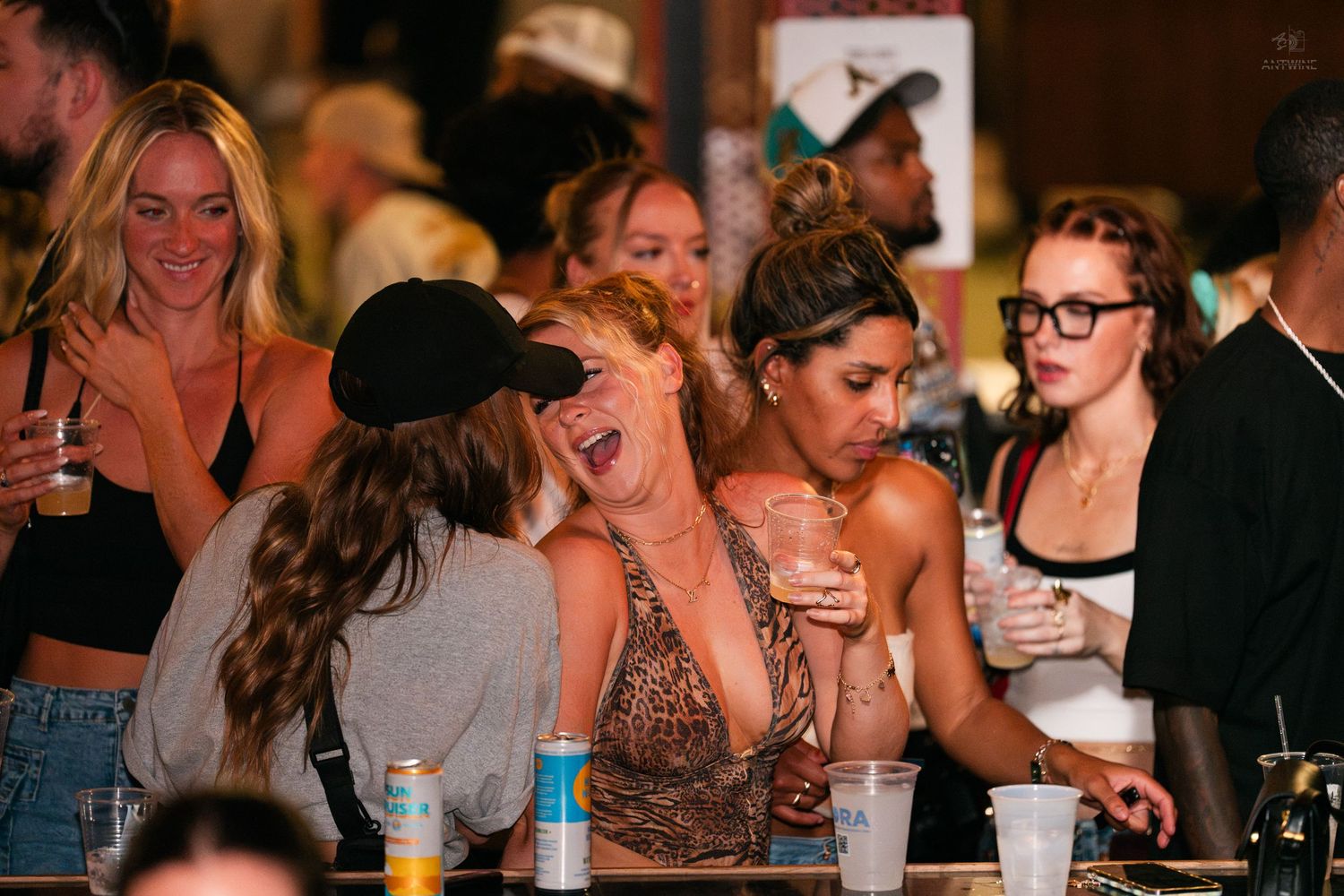 Group of women laughing and socializing together at a lively bar nightlife event.