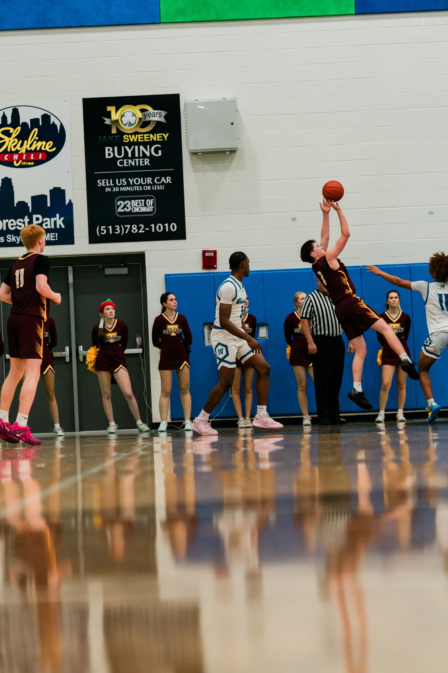 Turpin player launches a jump shot while Warriors defenders contest during a high school basketball game.