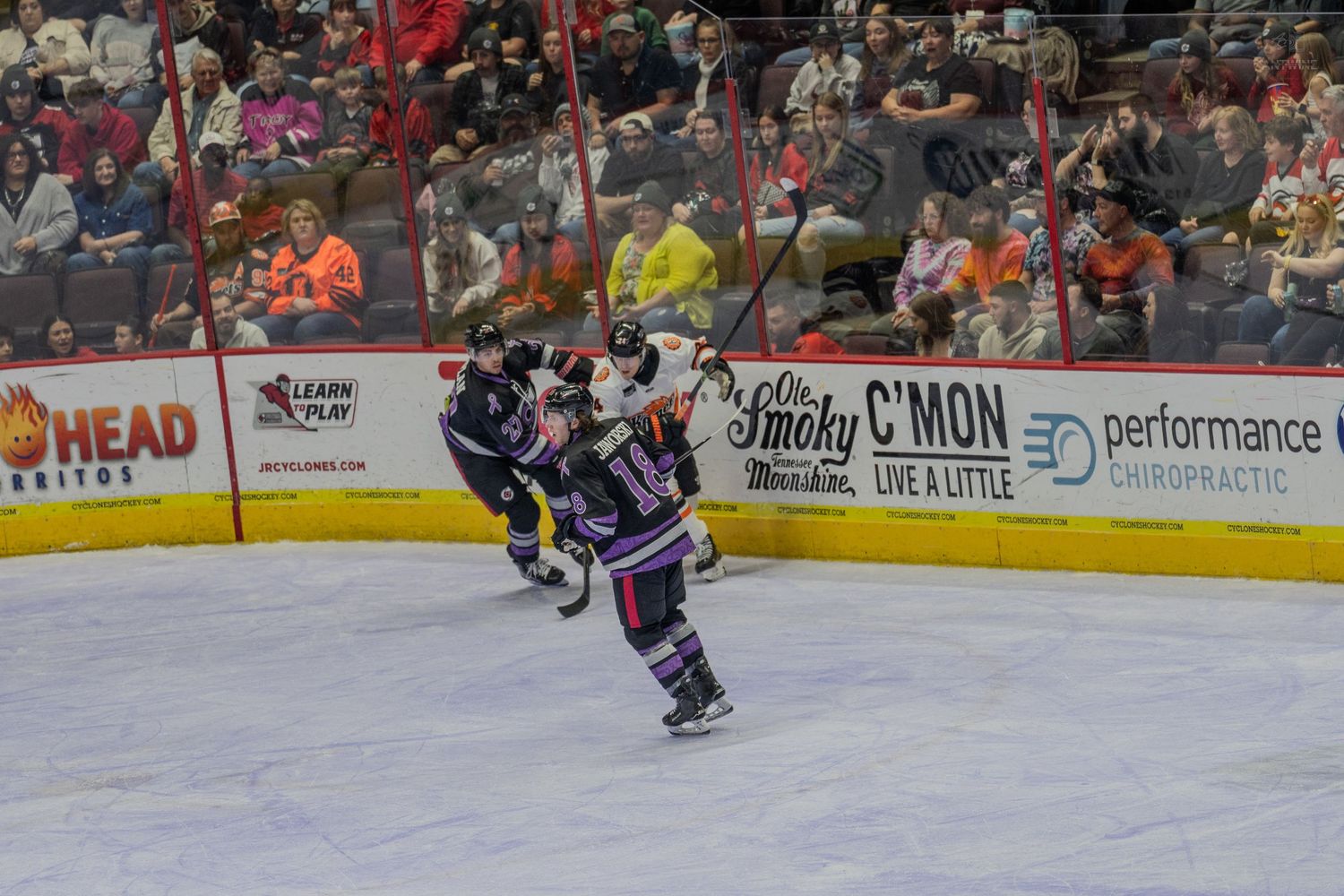 Hockey players collide during an intense play along the boards at a professional ice hockey game.