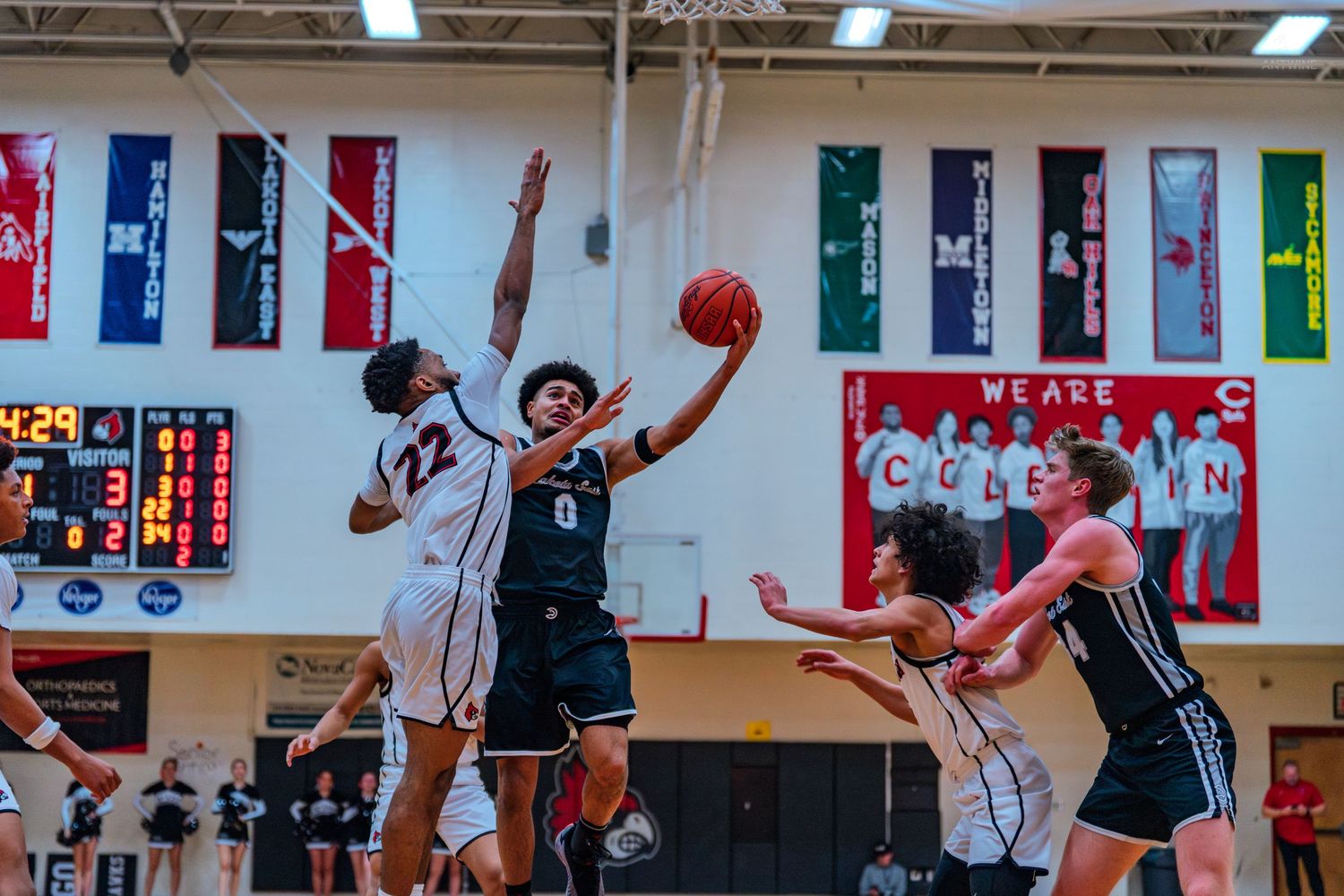 Lakota East player #0 drives to the basket against defender #22 during high school basketball game.