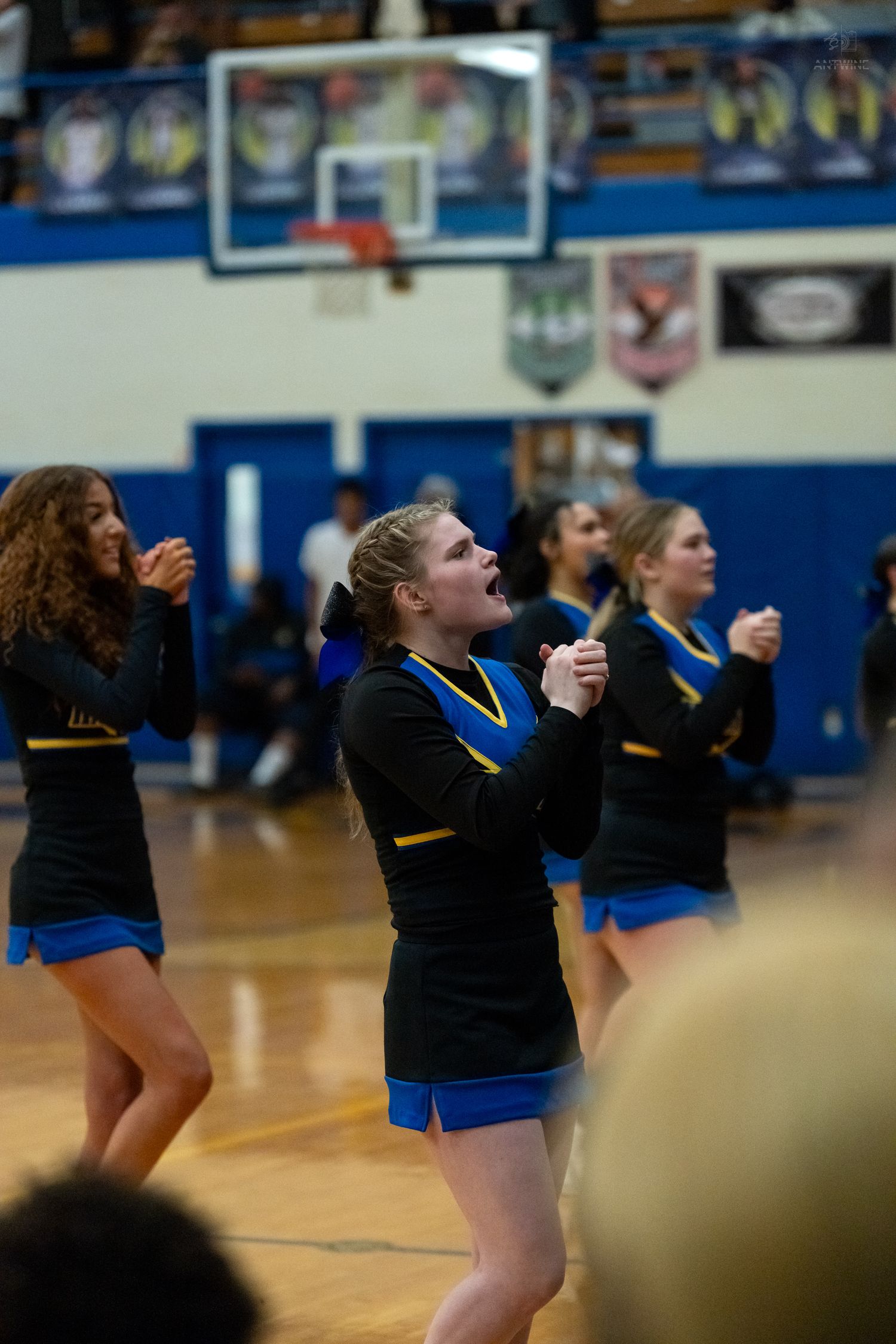 Knights cheerleaders in black and gold uniforms cheer enthusiastically during home basketball game.