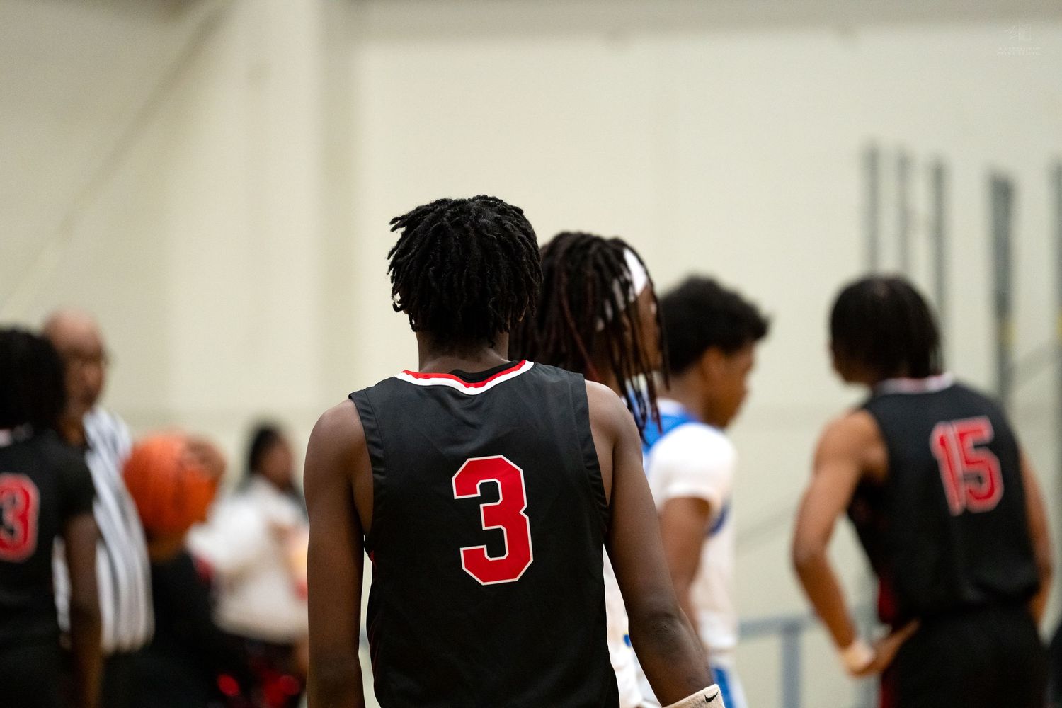 Basketball player wearing black jersey number 3 stands on court during high school game.