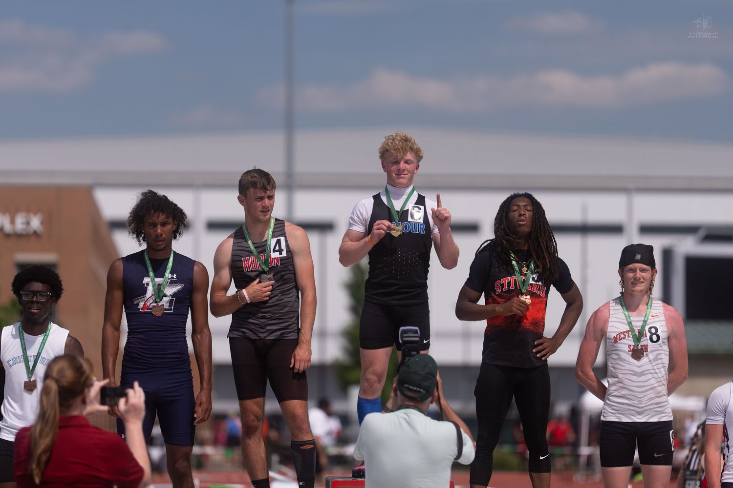 High school boys display medals on a podium at an OHSAA Division IV track and field championship meet.
