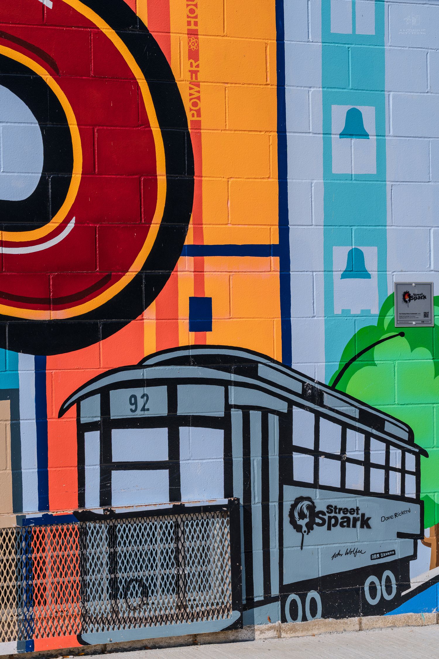 Colorful mural featuring a gray streetcar numbered 92 with Street Spark logo on a vibrant painted brick wall.