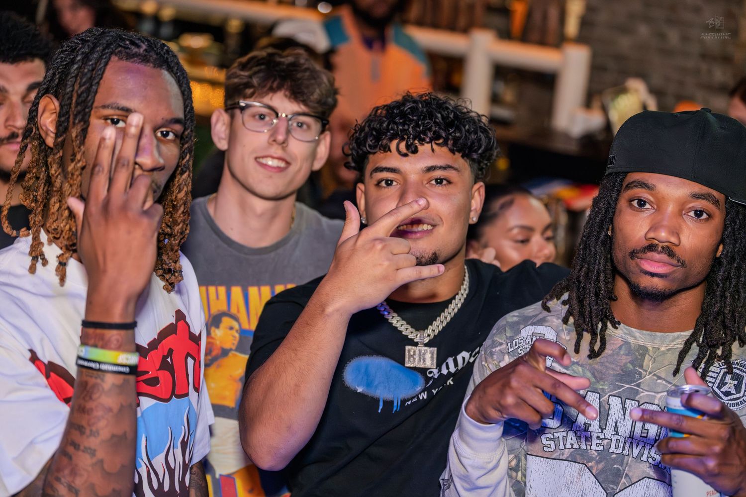 Four young men posing and smiling together at a fun nightlife bar event.