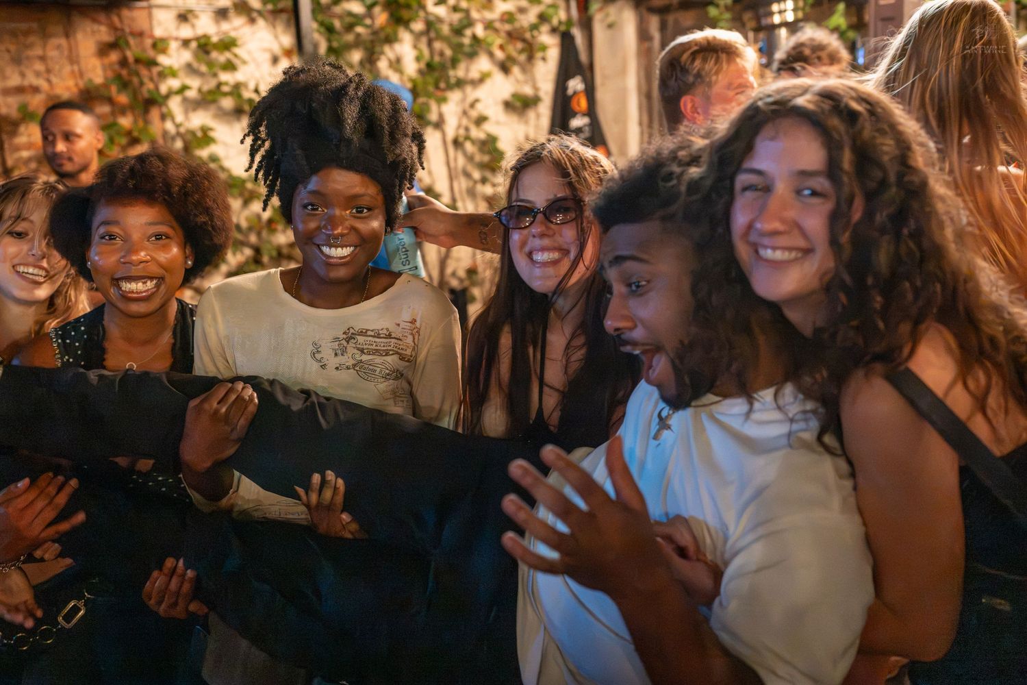 Group of young people laughing and enjoying themselves at a lively outdoor evening event.