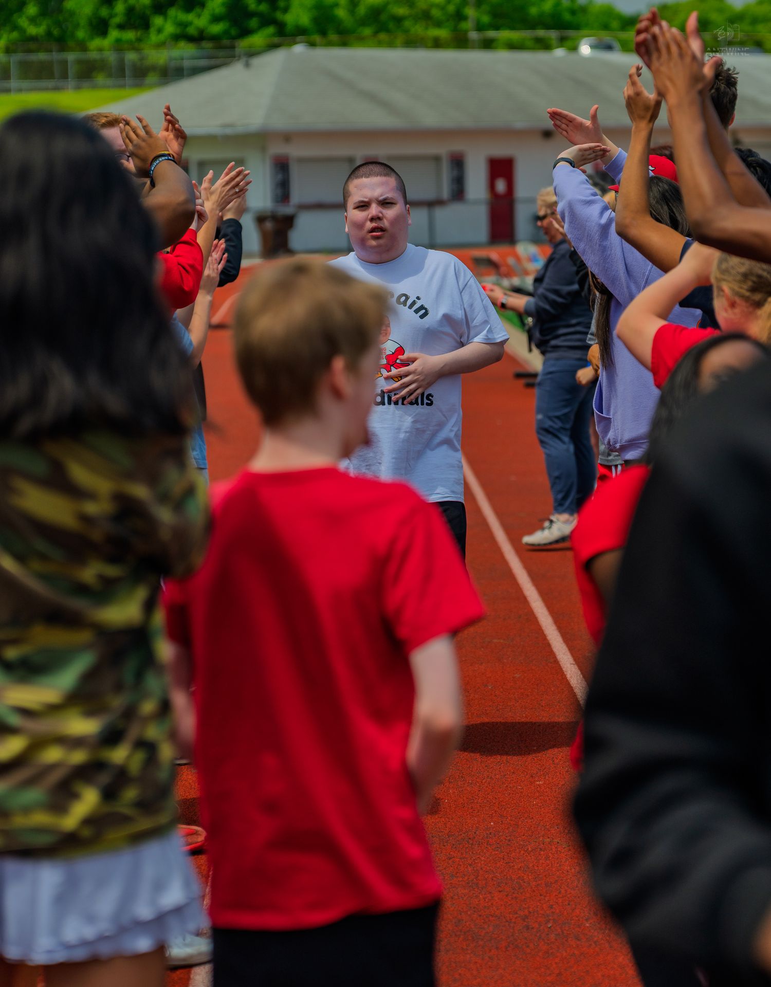 Athlete walks through a high-five tunnel on a red track during a Special Olympics event.