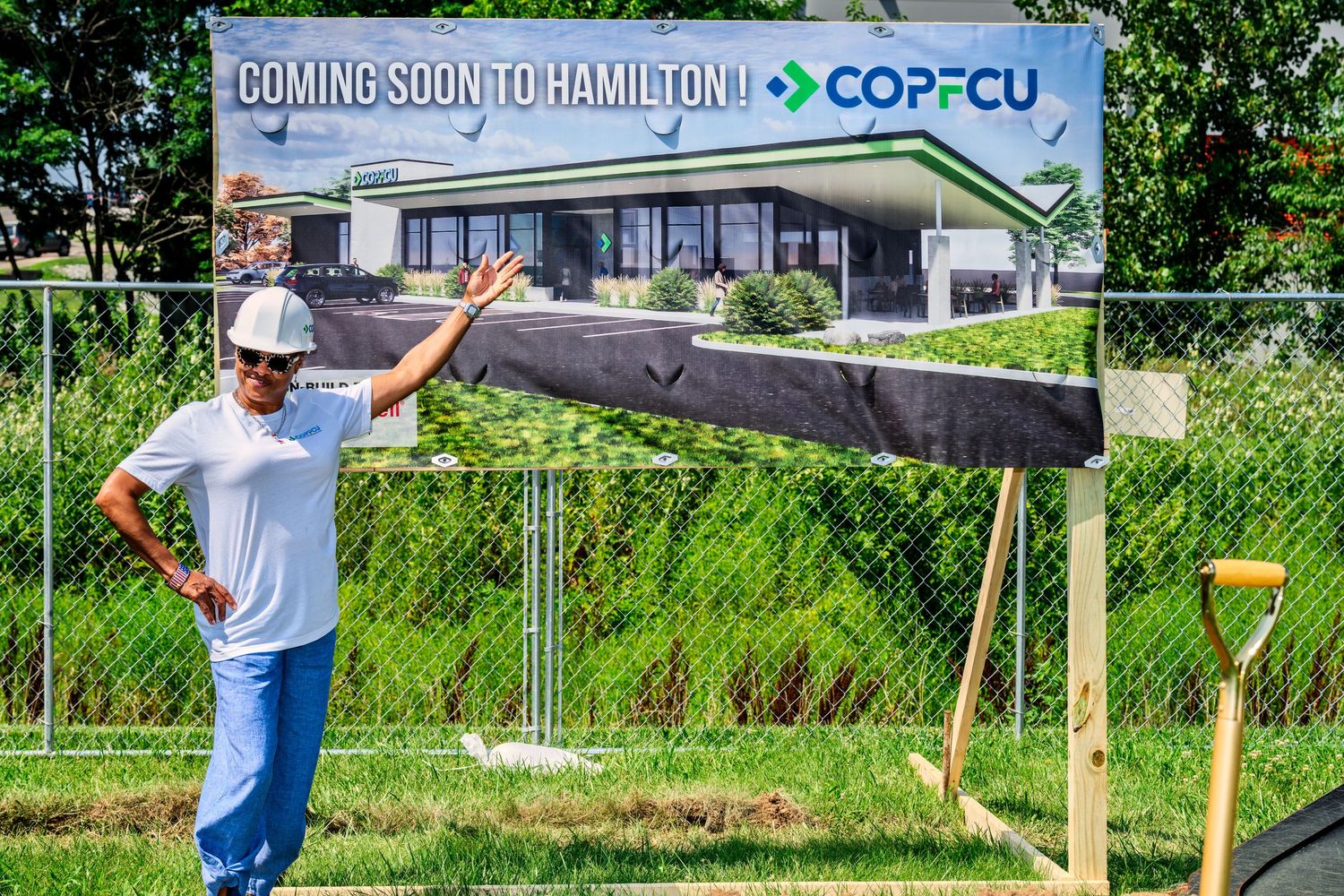 Individual celebrating in front of COPFCU Coming Soon to Hamilton banner at groundbreaking site.