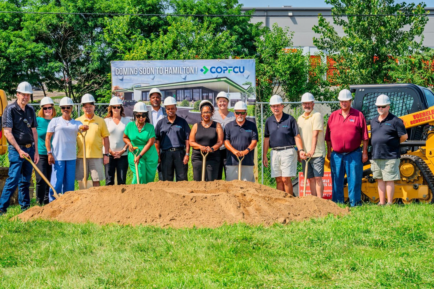 Team members wearing hard hats pose with golden shovels at COPCU credit union Hamilton groundbreaking event.