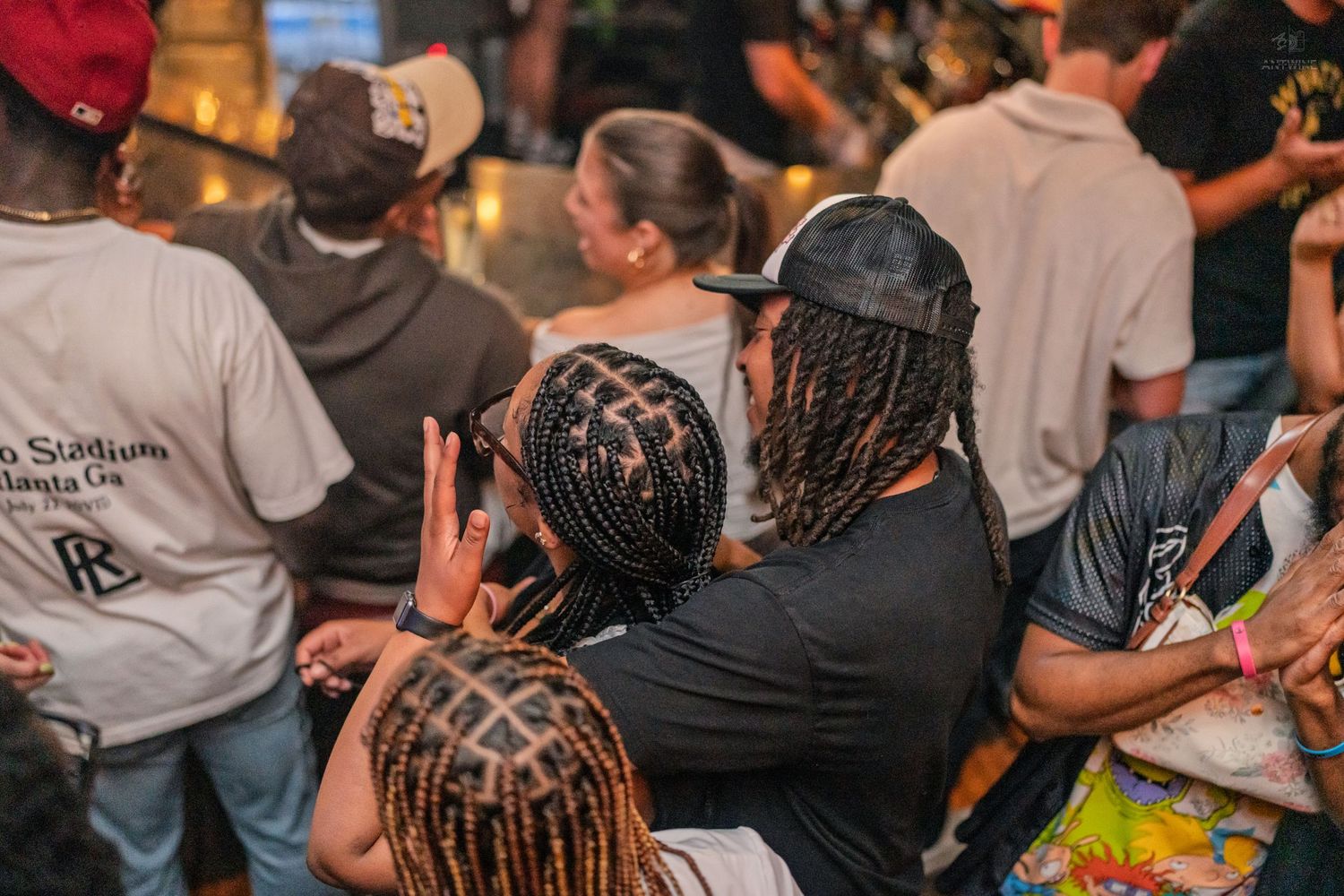 Group of friends with braided hairstyles hugging and posing at a lively nightclub event.