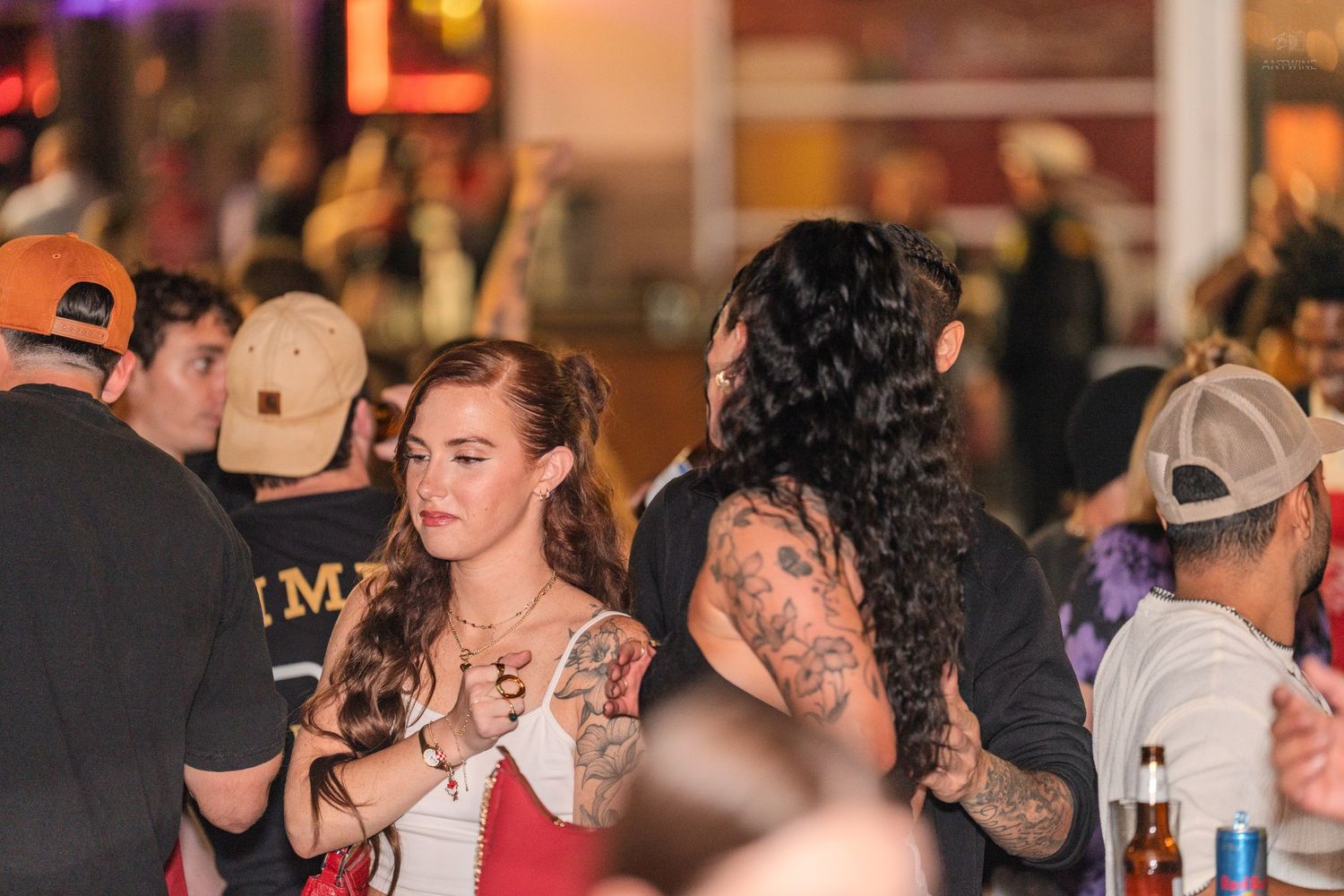 Two women dancing and socializing together at a lively crowded nightclub or bar event.