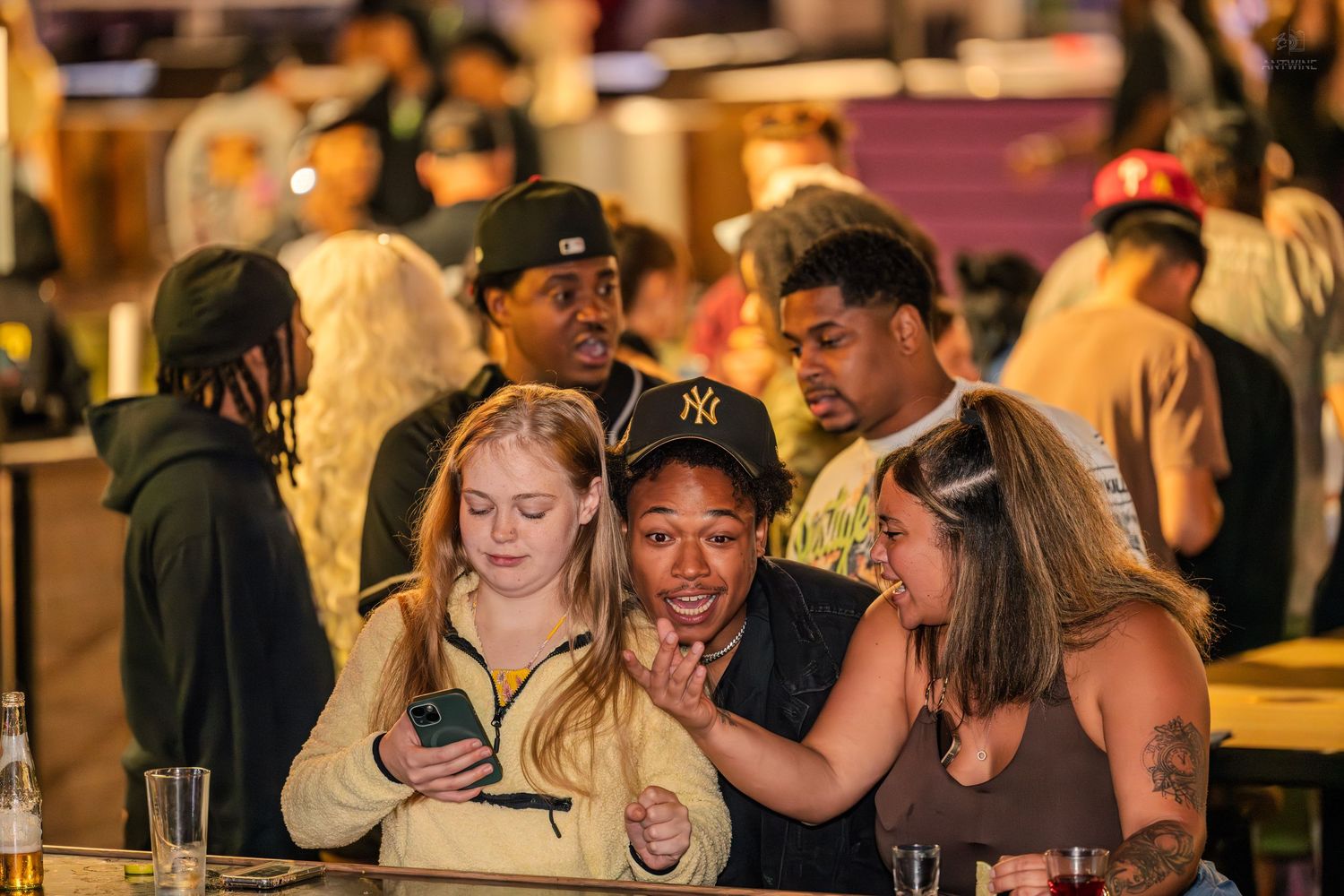 Group of friends smiling and looking at a phone at a nightlife event.