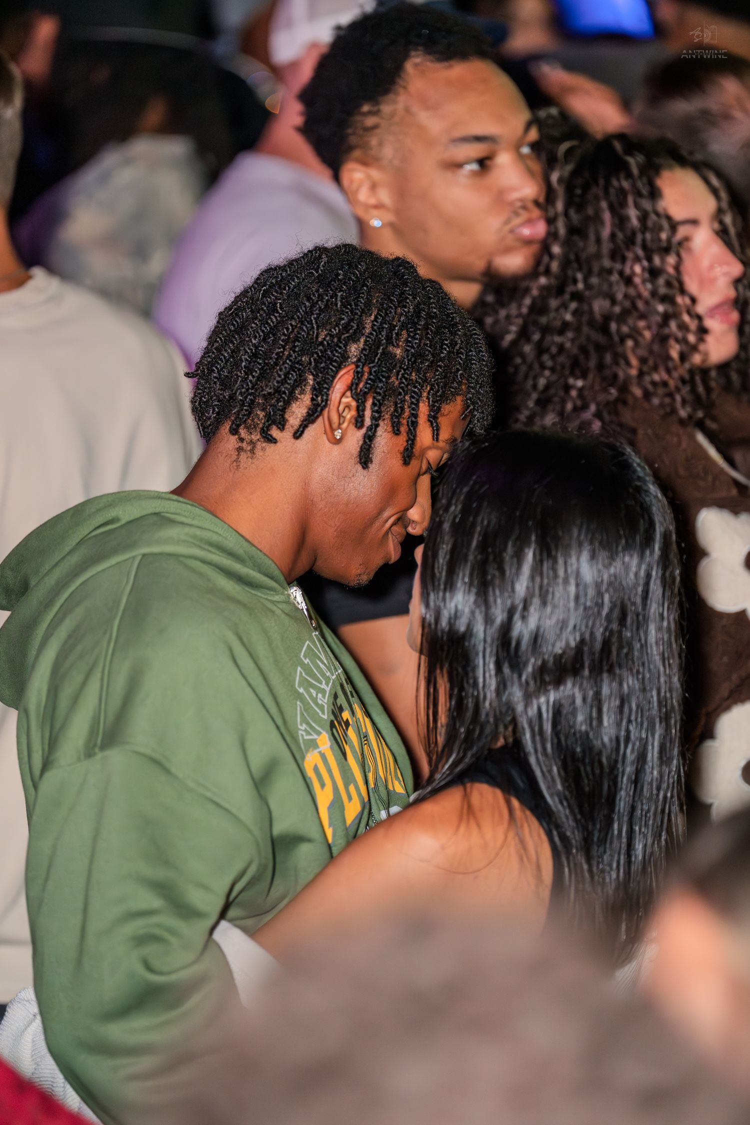 Couple kissing in a crowded nightclub or concert venue.