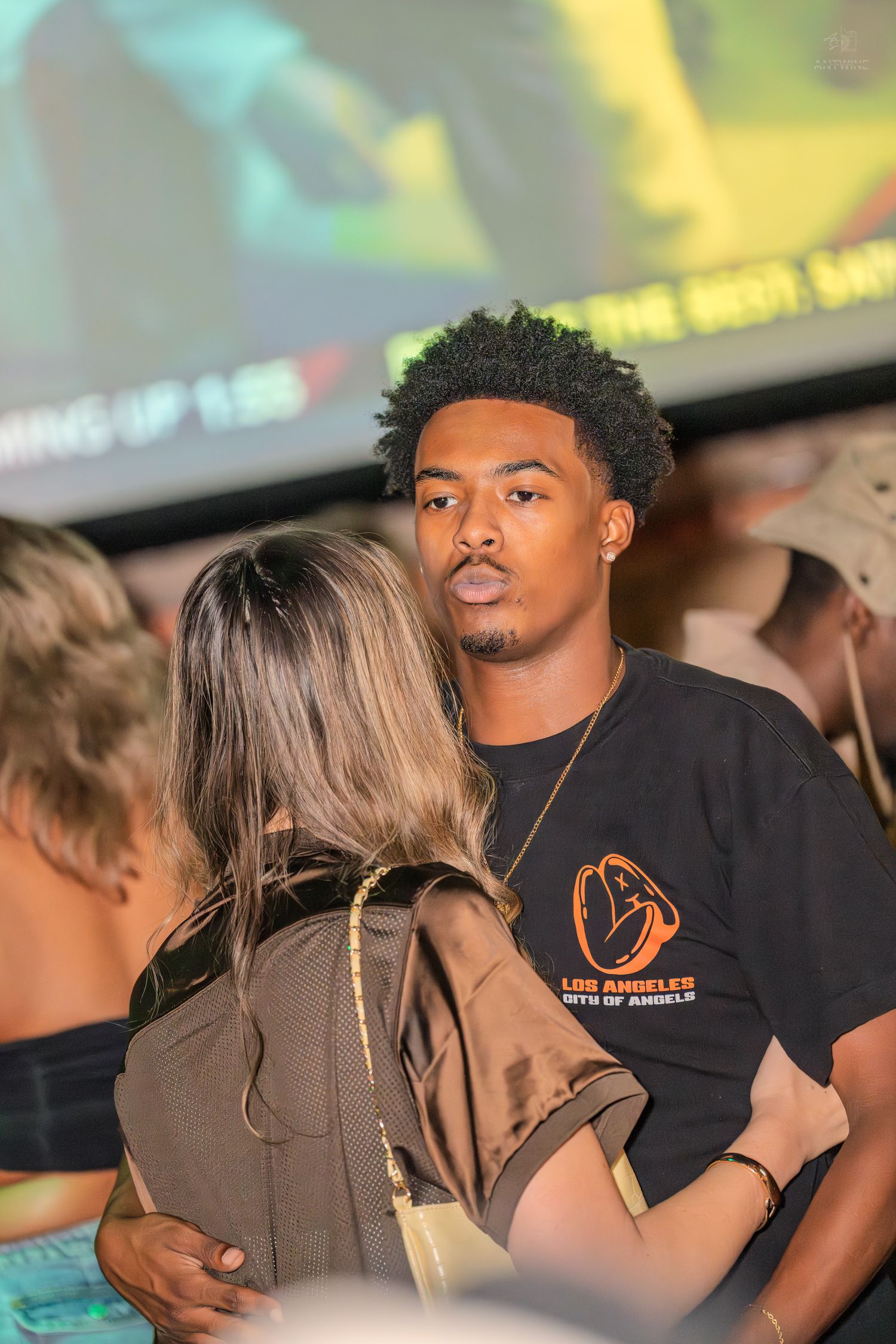 Young man in Los Angeles Angels shirt talking with a woman at a party.