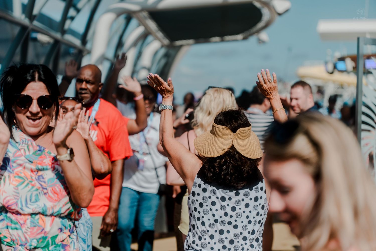 Cheerful group of people dancing with hands raised on a cruise ship deck.