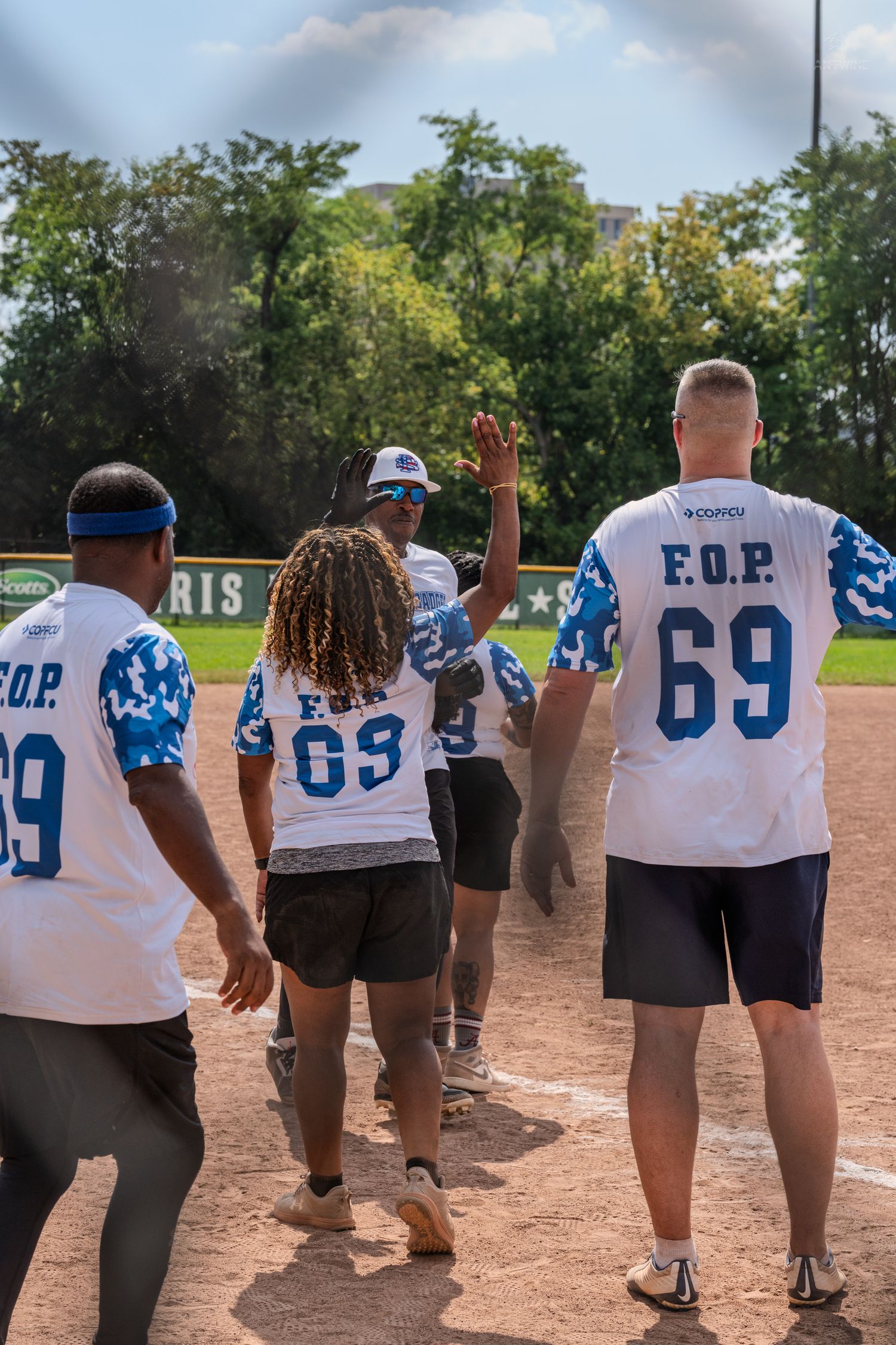 EOP softball team players walk toward home plate celebrating a score during an outdoor game.