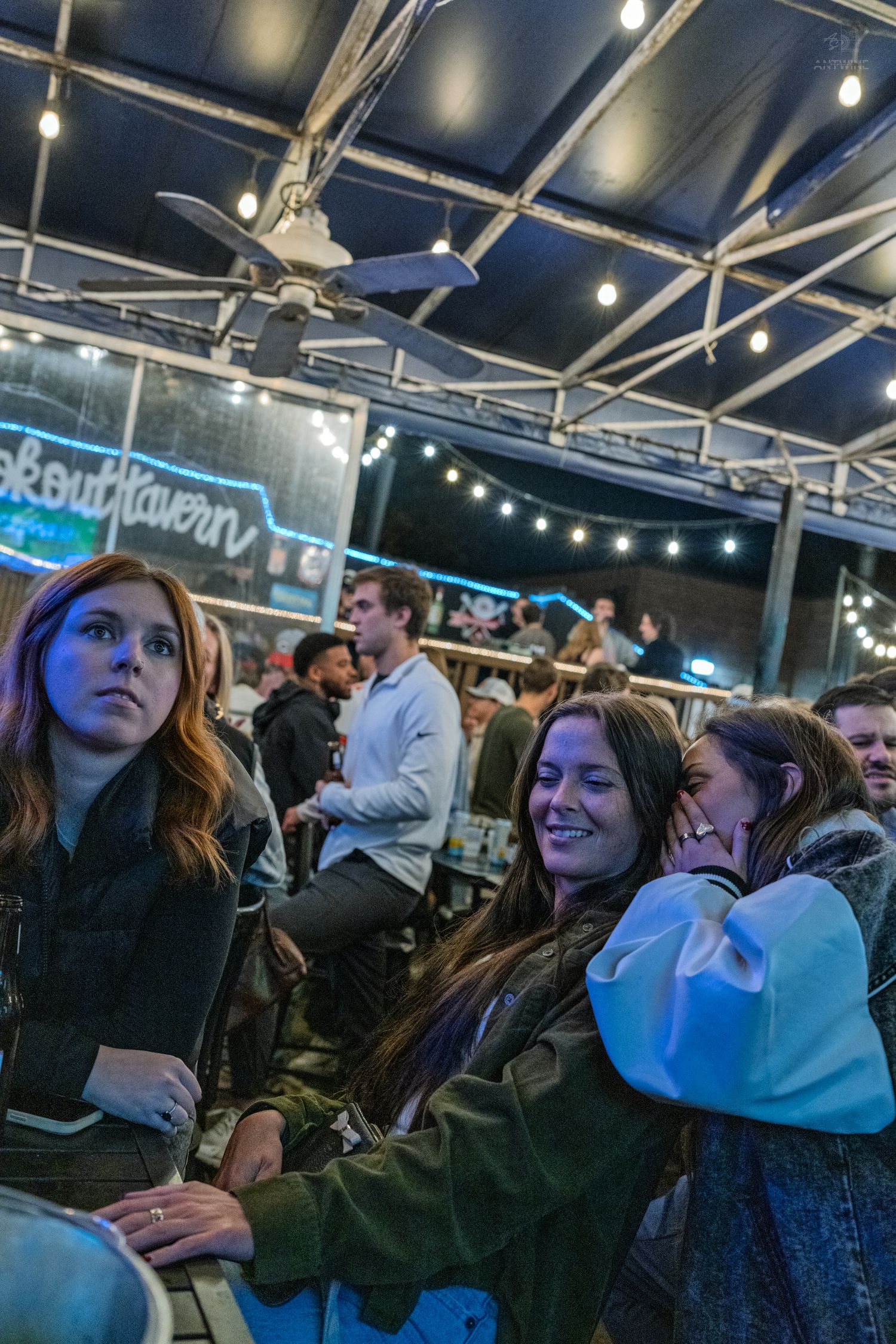 Group of young women enjoying a live event at Lookout Tavern under string lights at night.