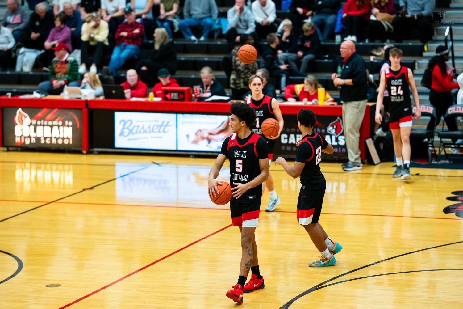 High school basketball player number 5 prepares to shoot during a game in a red and black gymnasium.
