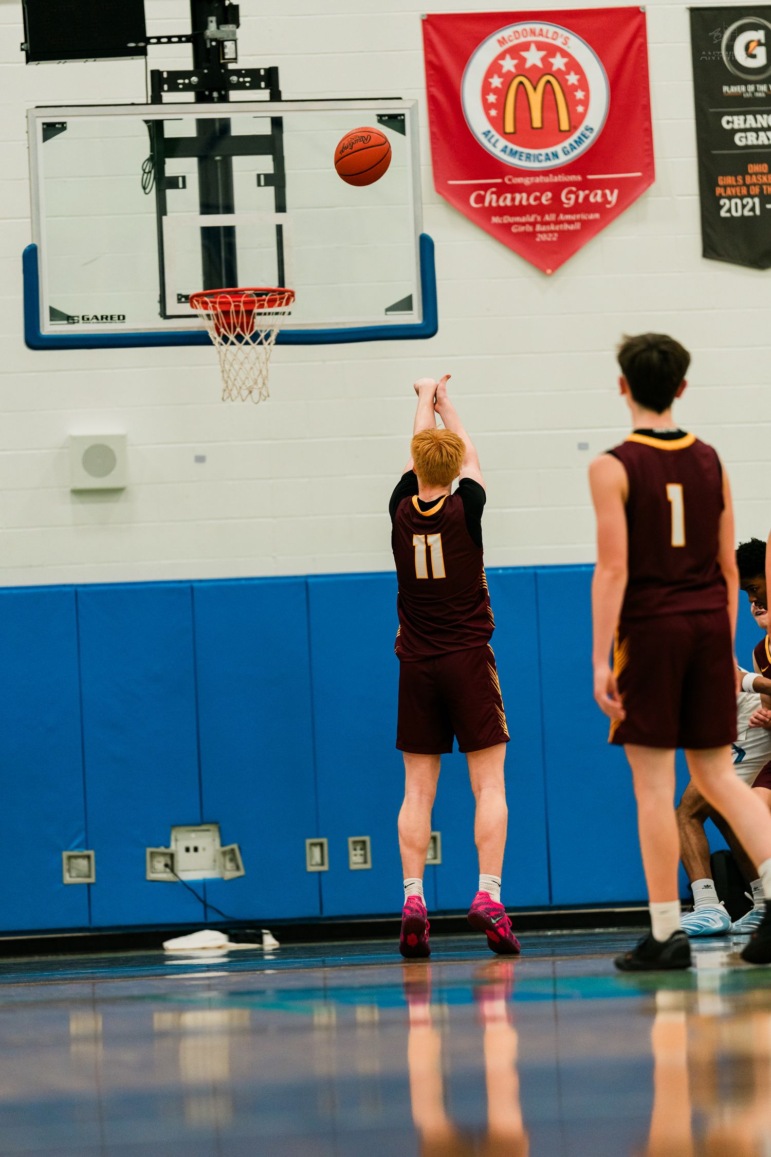 Player #11 in maroon uniform shoots free throw under McDonald's All-American banner.