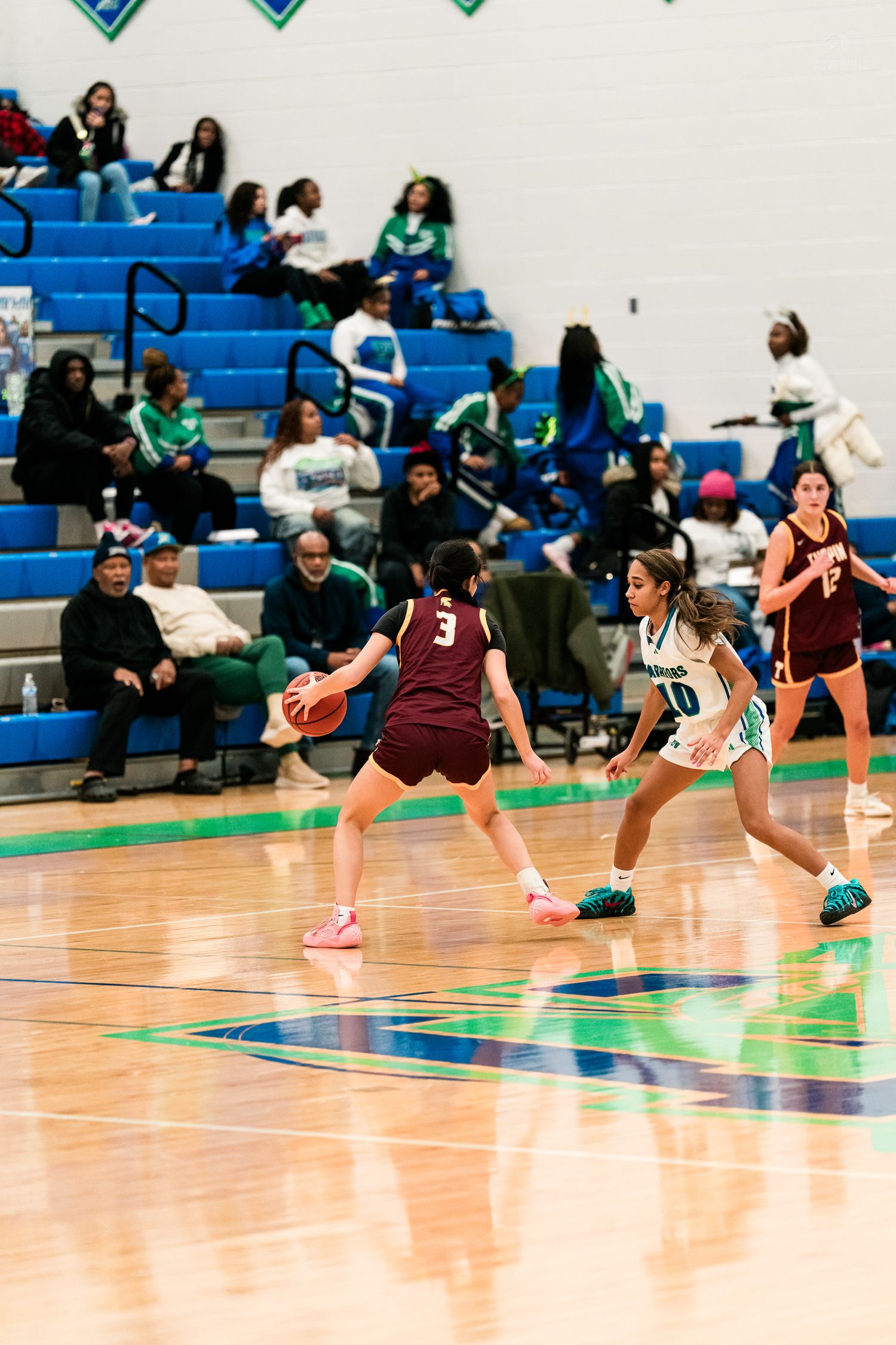 A Warriors player number 10 defends a Turpin player number 3 who dribbles the ball during a girls basketball game.